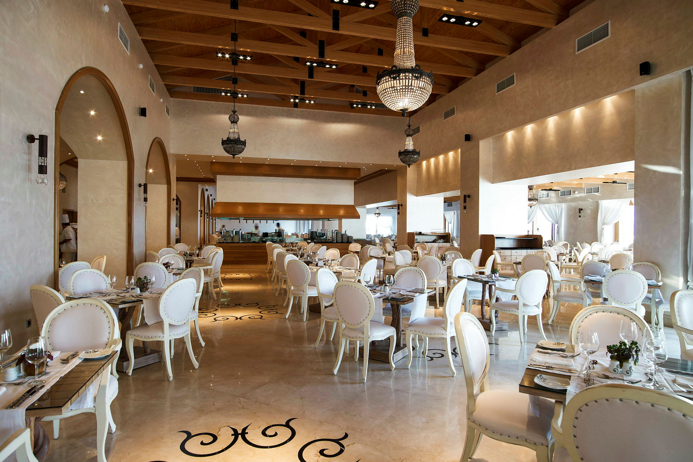 En elegant restaurang med vita stolar och bord, dekorerad med ljuskronor. (AI-genererad text)