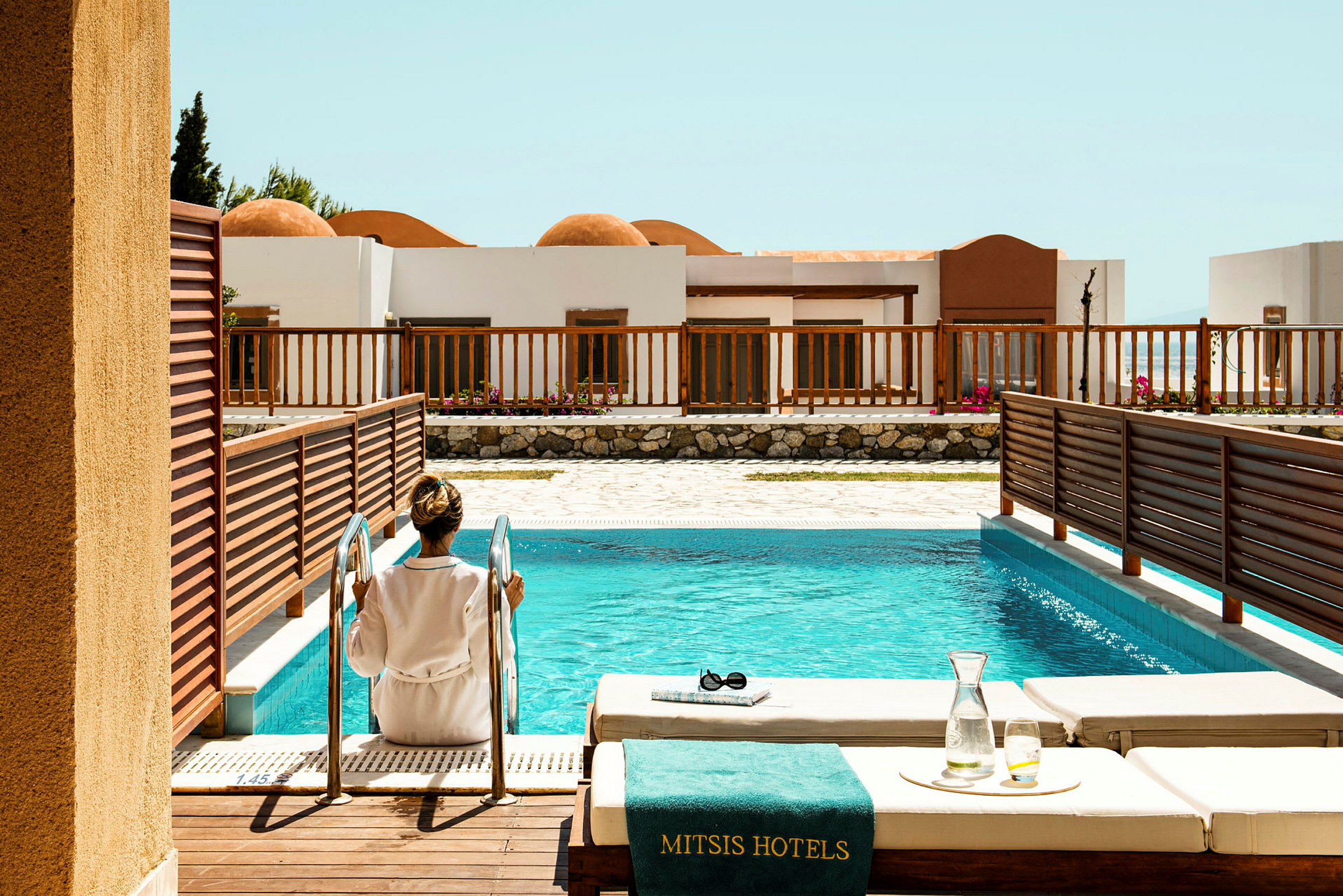 En person sitter vid stegen till en hotellpool. (AI-genererad text)