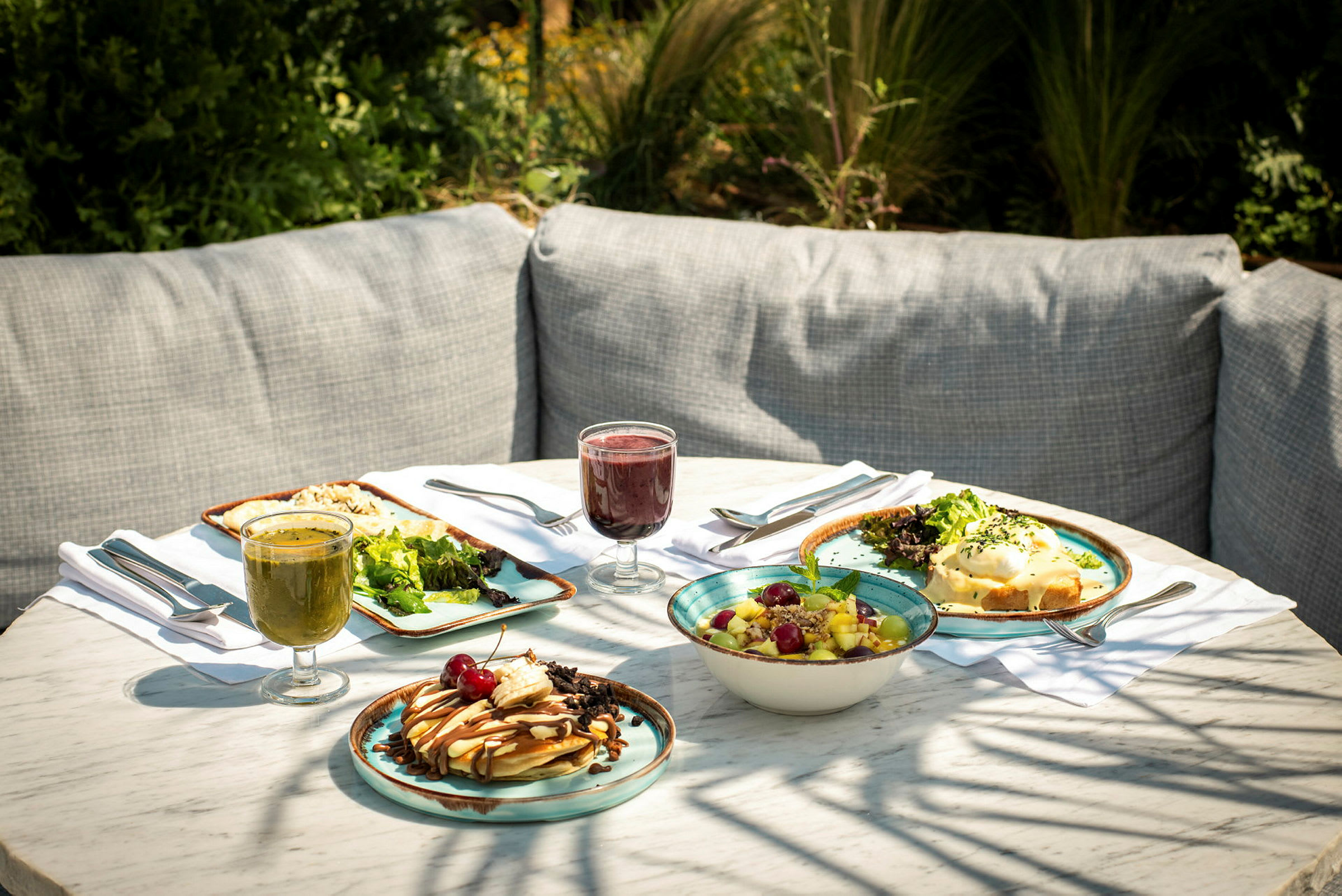 En dukad bord med olika tallrikar, sallad, maträtter och glas med drycker. (AI-genererad text)