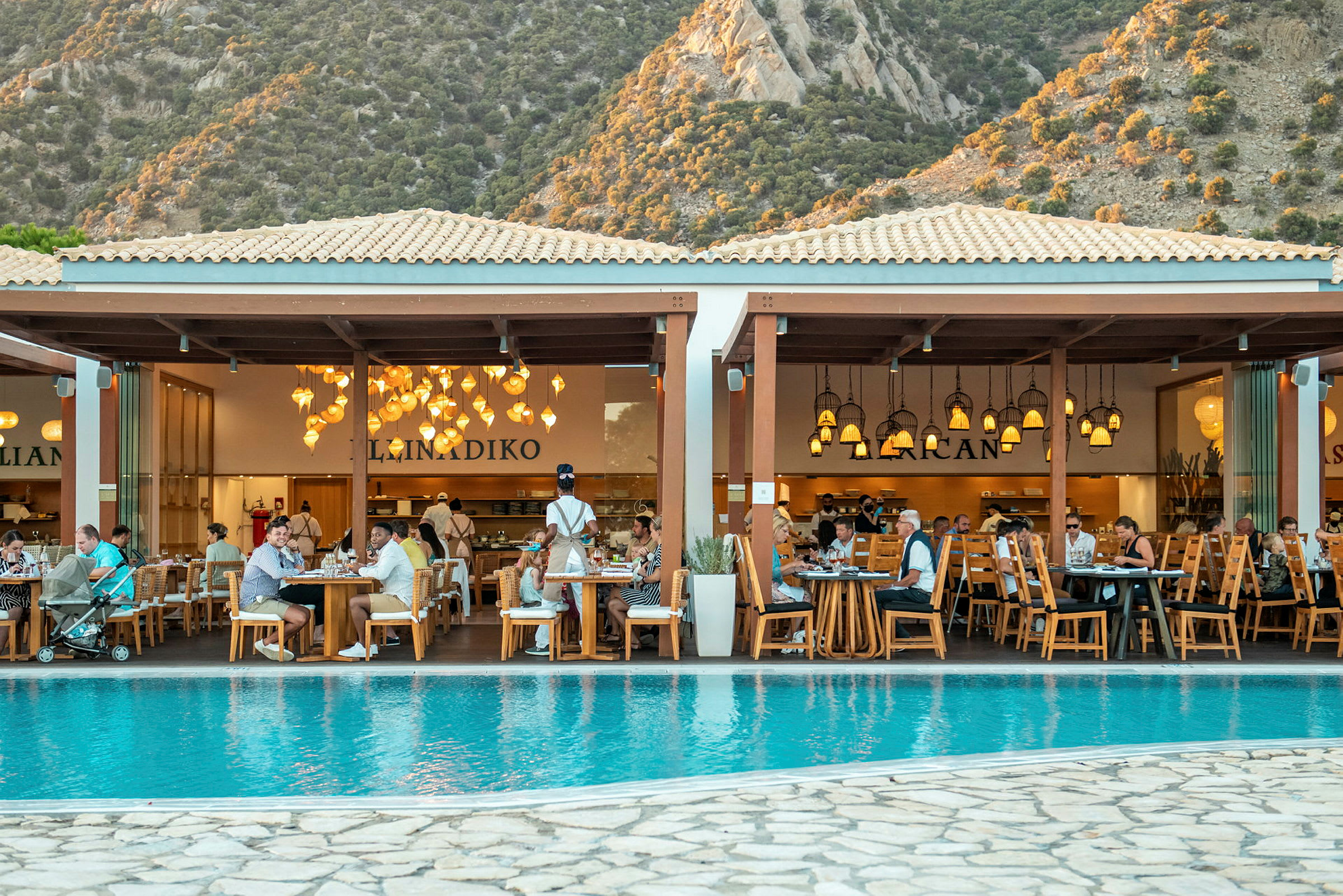En restaurang vid en pool med berg i bakgrunden. (AI-genererad text)