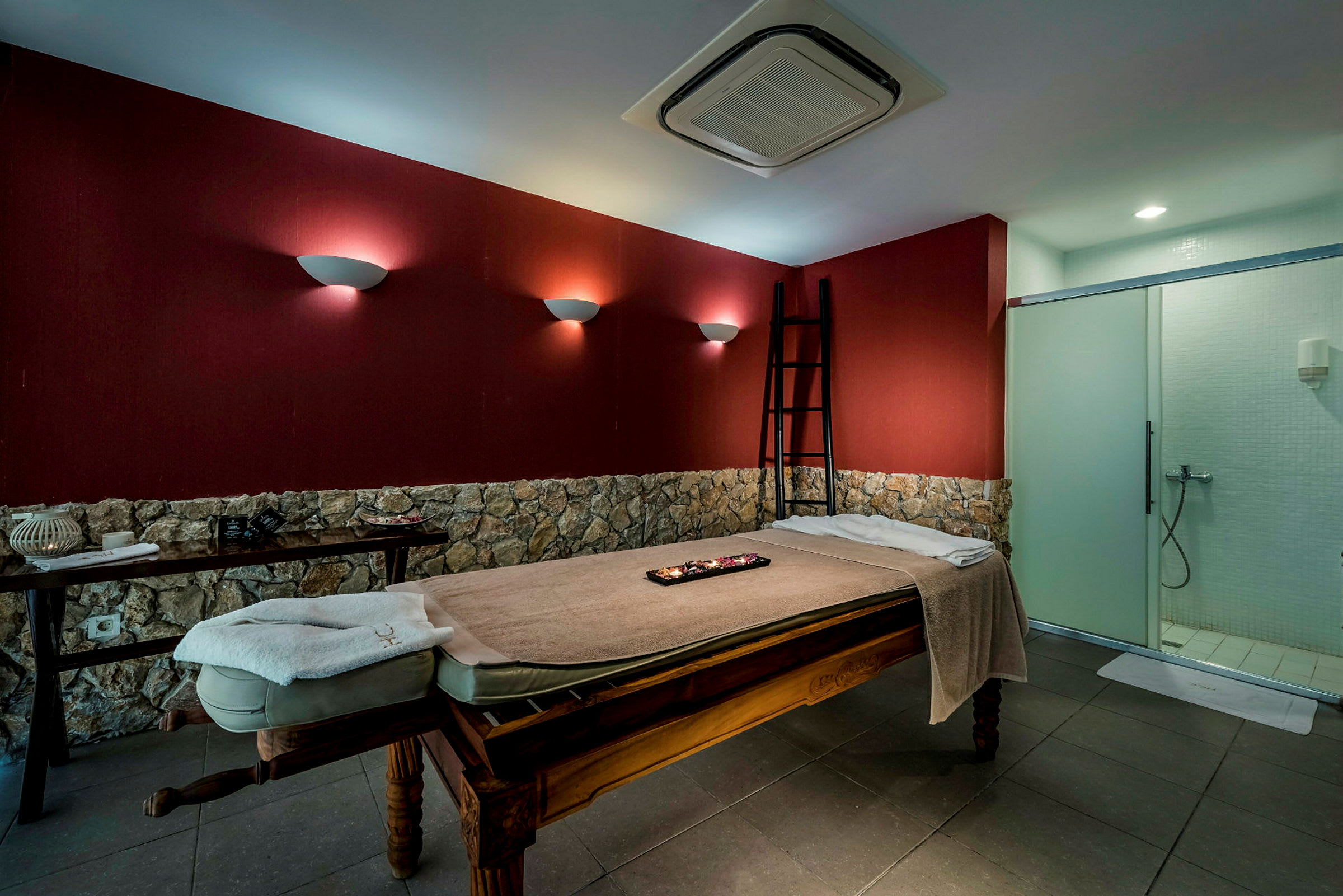 En massagesäng i ett rum med röda väggar och stenpanel. (AI-genererad text)