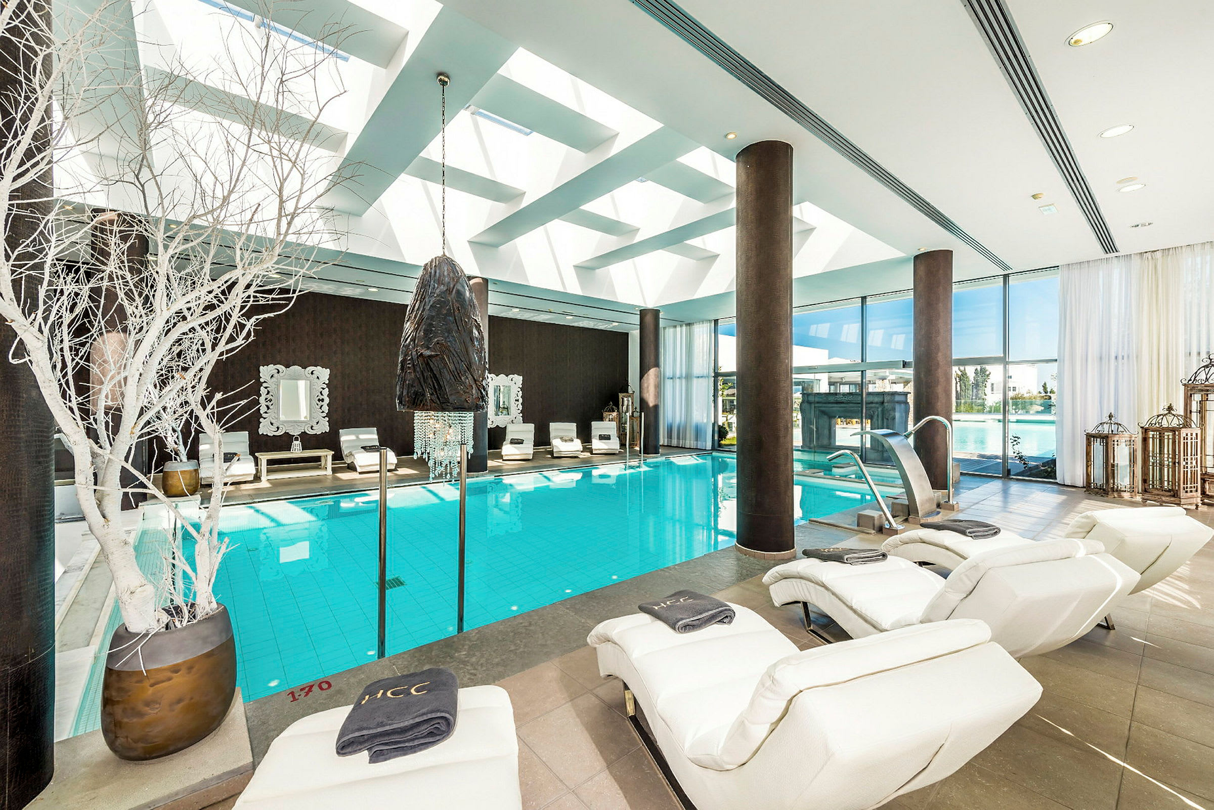 Inomhuspool med relaxstolar och stora fönster. (AI-genererad text)