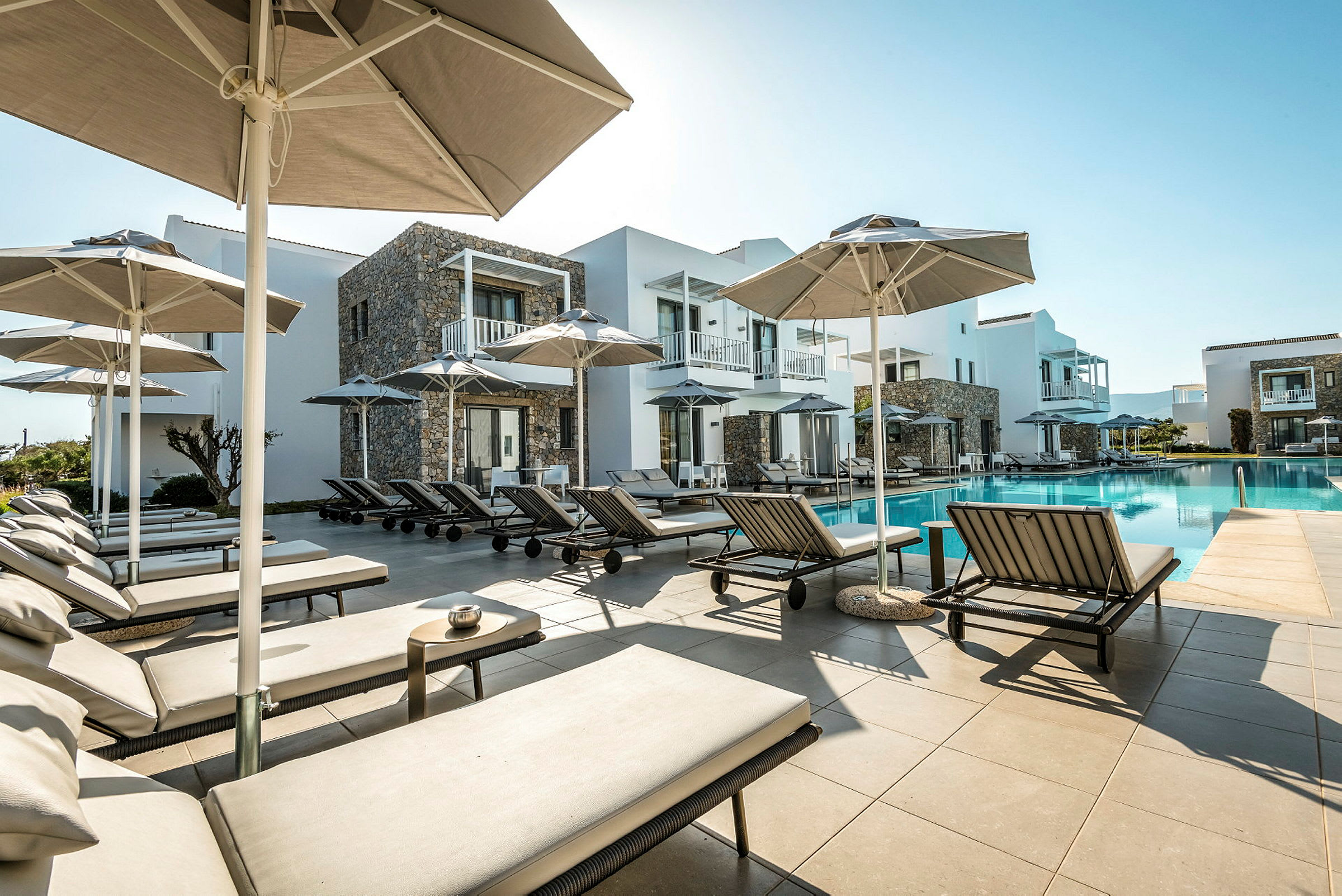 Poolområde med solstolar och parasoller vid hotellbyggnader. (AI-genererad text)