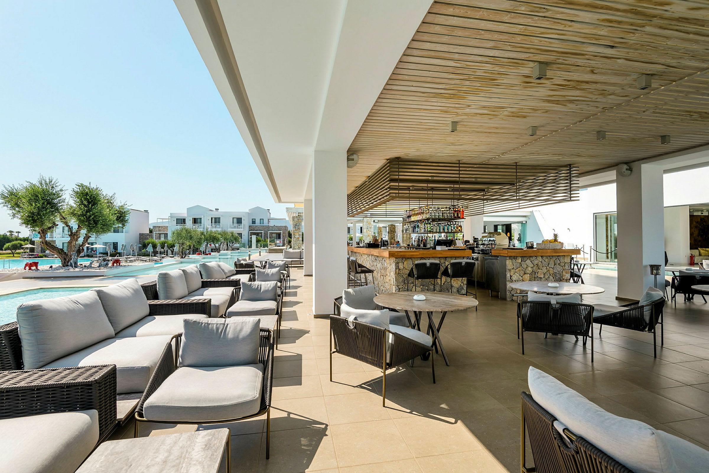 Utomhus loungeområde med bord och stolar nära en pool och bar. (AI-genererad text)