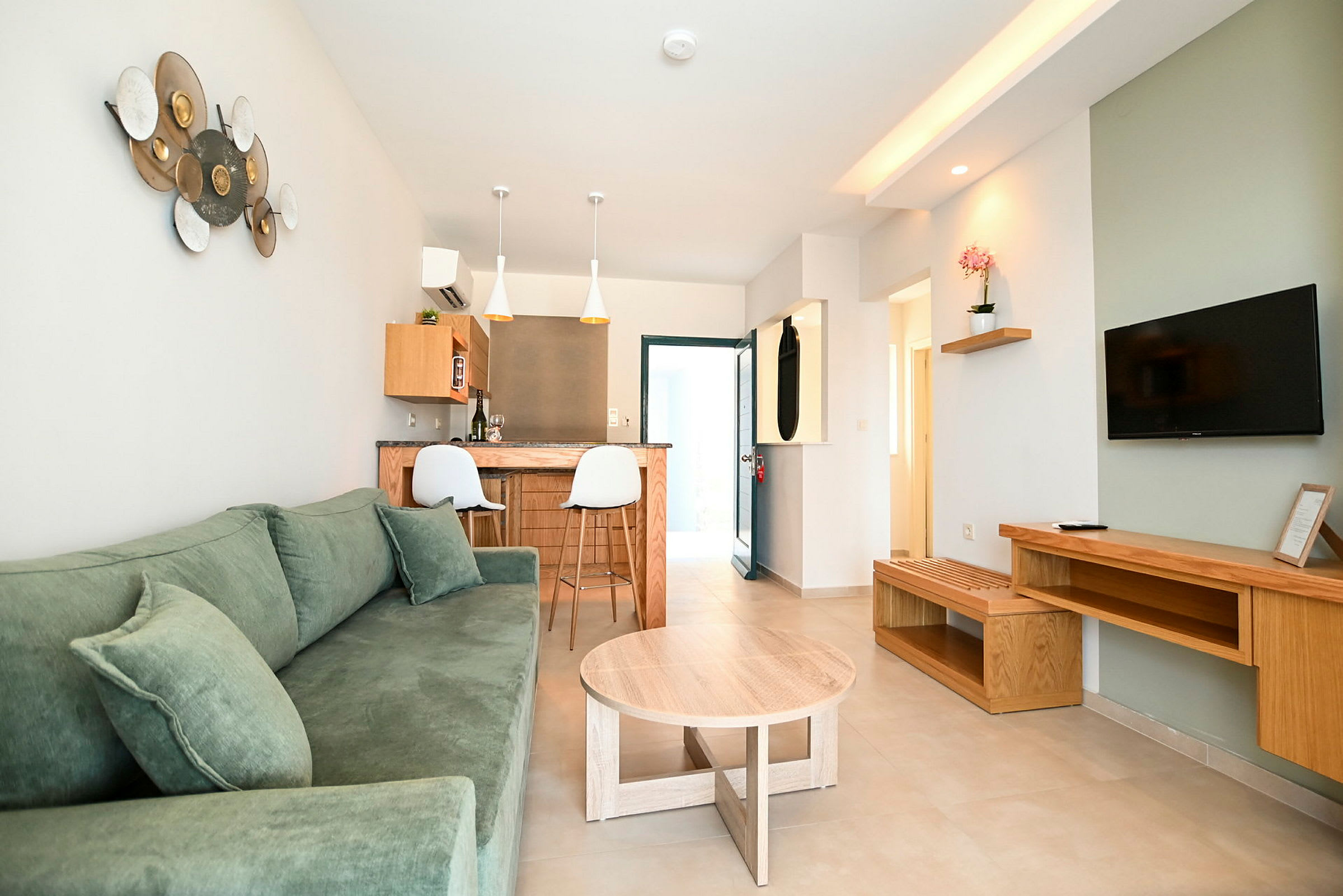 Ett modernt vardagsrum med grön soffa, träbord och TV på väggen. (AI-genererad text)