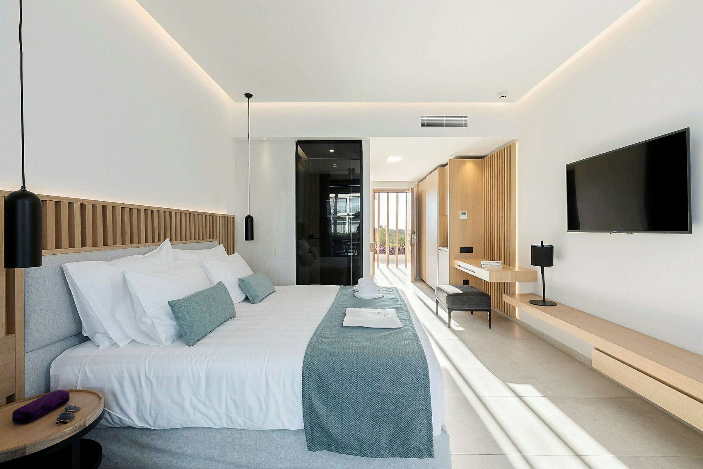 Modernt hotellrum med dubbelsäng, bortre fönster och inredning i ljusa toner. (AI-genererad text)