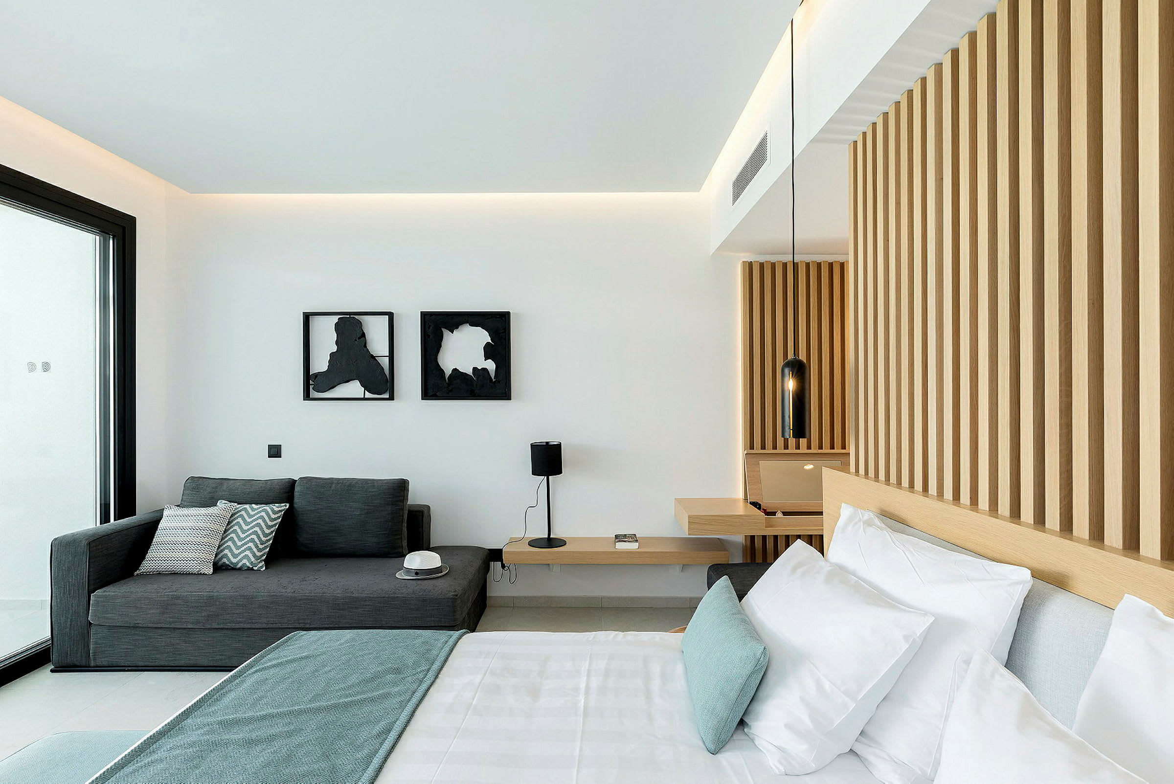 Ett modernt hotellrum med en säng, en soffa och en träpanelvägg. (AI-genererad text)