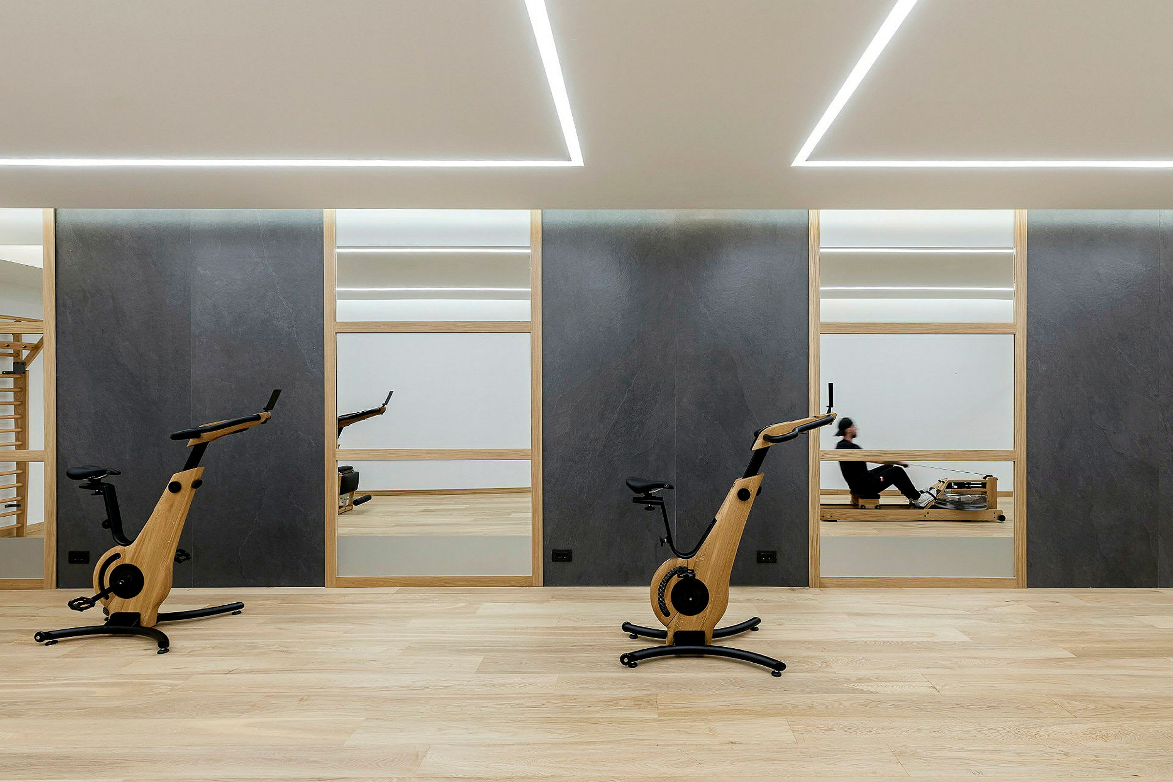 Gym med två träningscyklar och en person på en roddmaskin. (AI-genererad text)