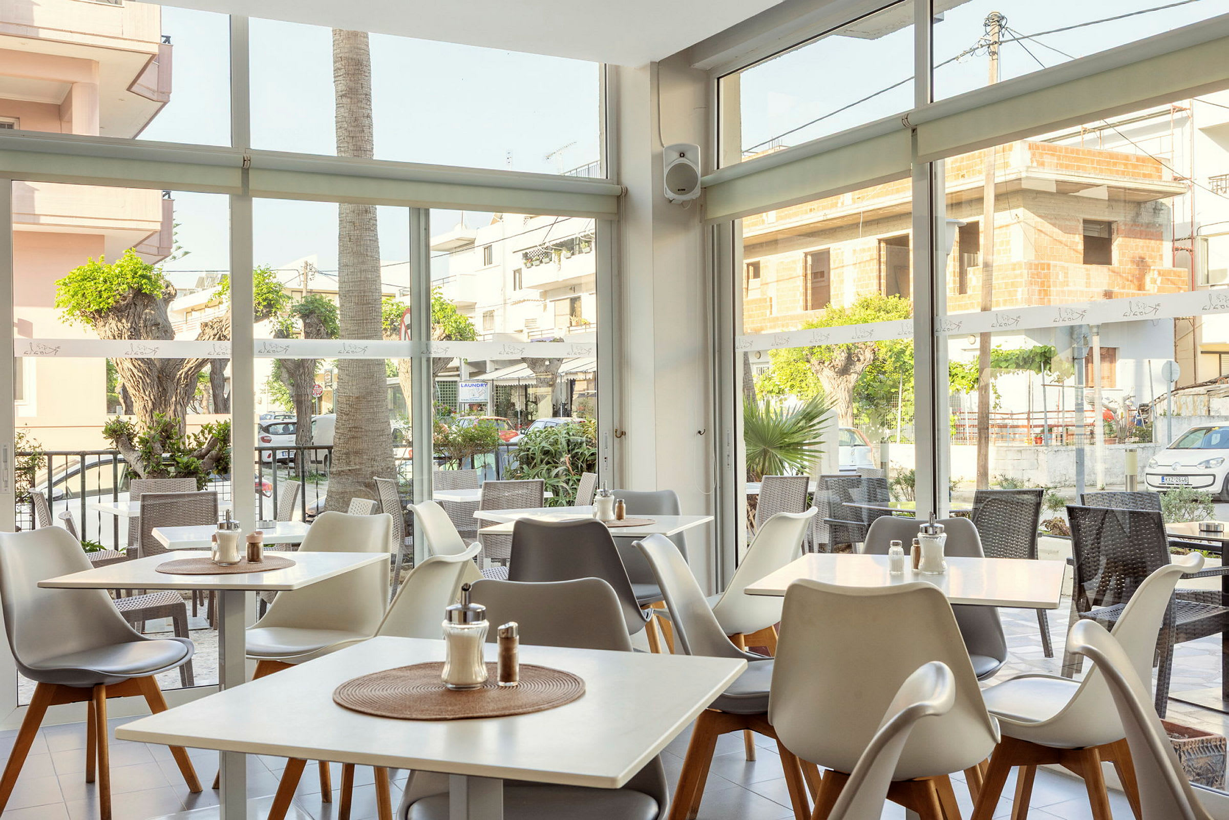 En ljus restaurang med fönster ut mot gatan och utomhusbord. (AI-genererad text)