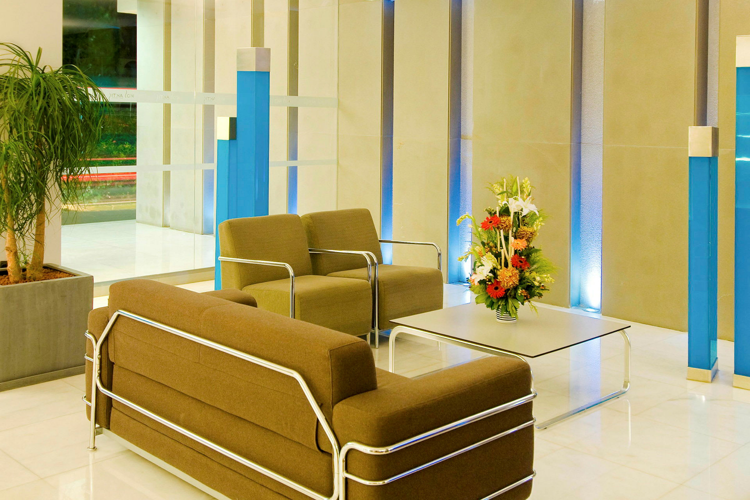Bild av en hotellobby med stolar och bord, prydd med en blomsterarrangemang. (AI-genererad text)