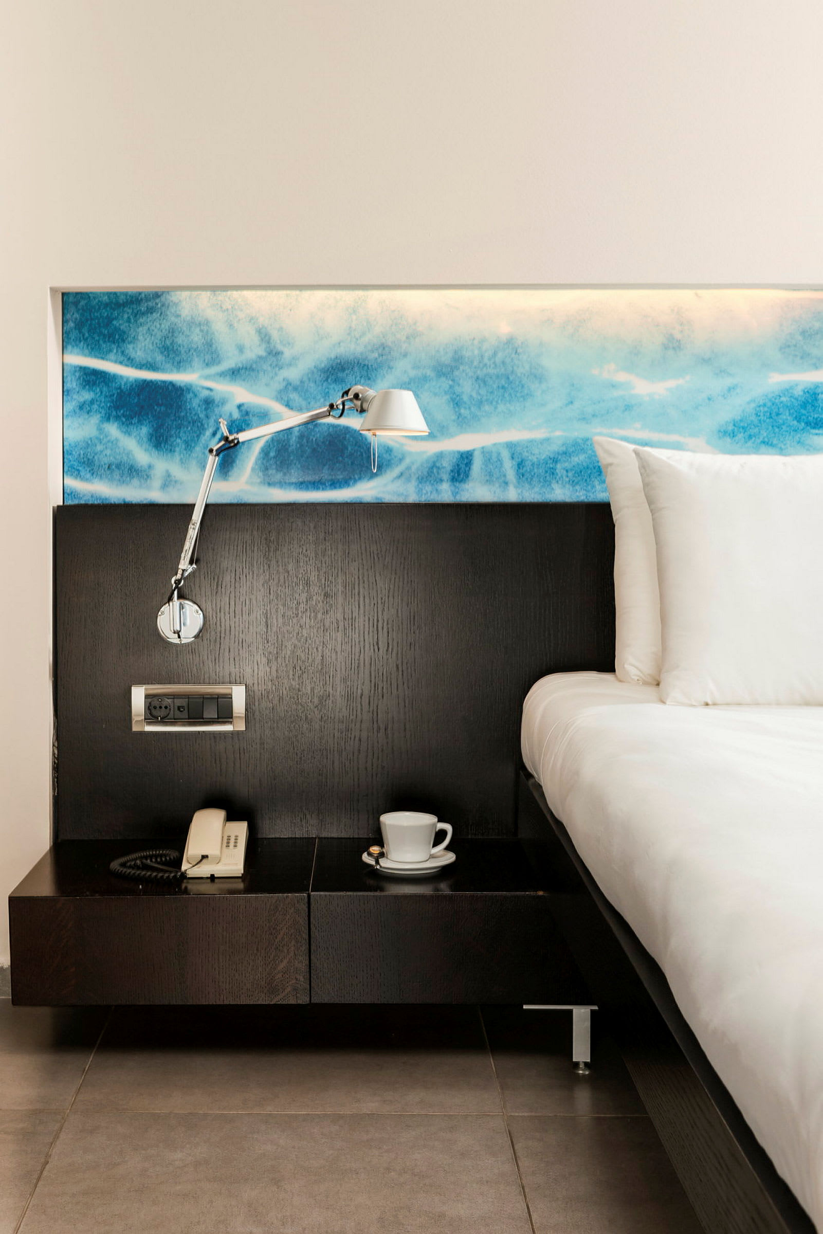Hotellrum med säng, sängbord, lampa och telefon. (AI-genererad text)
