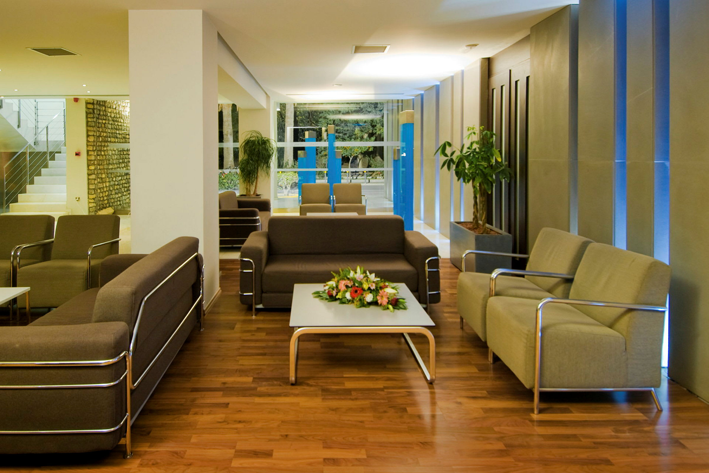En modern loungemiljö med soffor, fåtöljer och ett bord med blommor på. (AI-genererad text)