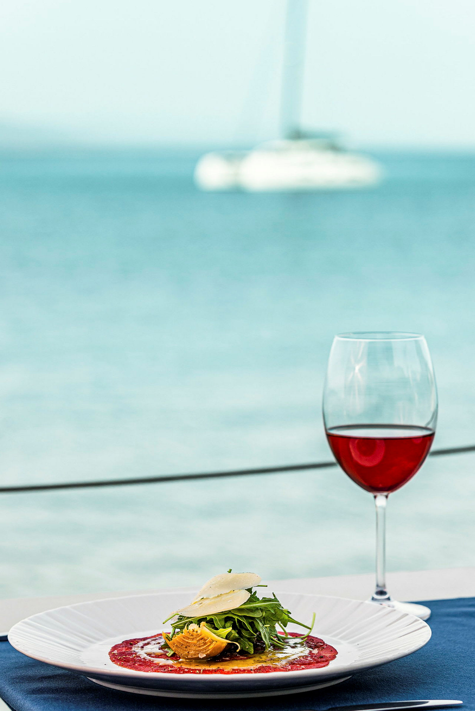 En tallrik med mat och ett glas rödvin vid havet. (AI-genererad text)