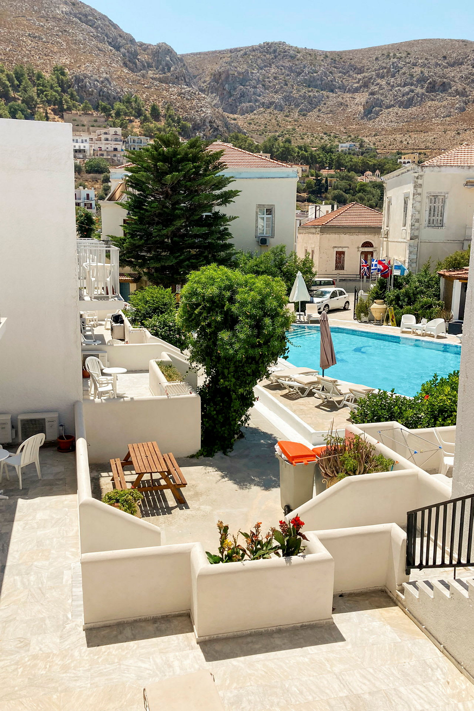 Bild av gård med utemöbler, pool och omgivande hus samt berg i bakgrunden. (AI-genererad text)