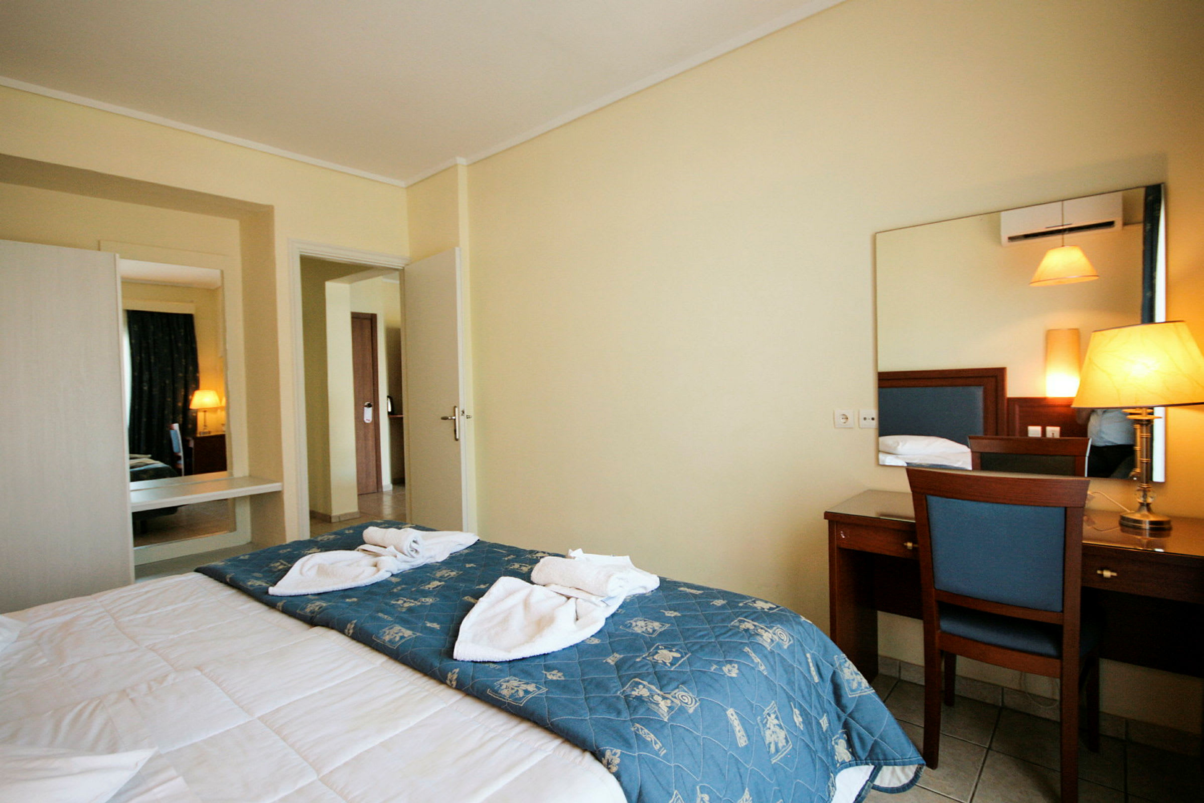 Interiör av ett hotellrum med en säng, spegel och skrivbord. (AI-genererad text)