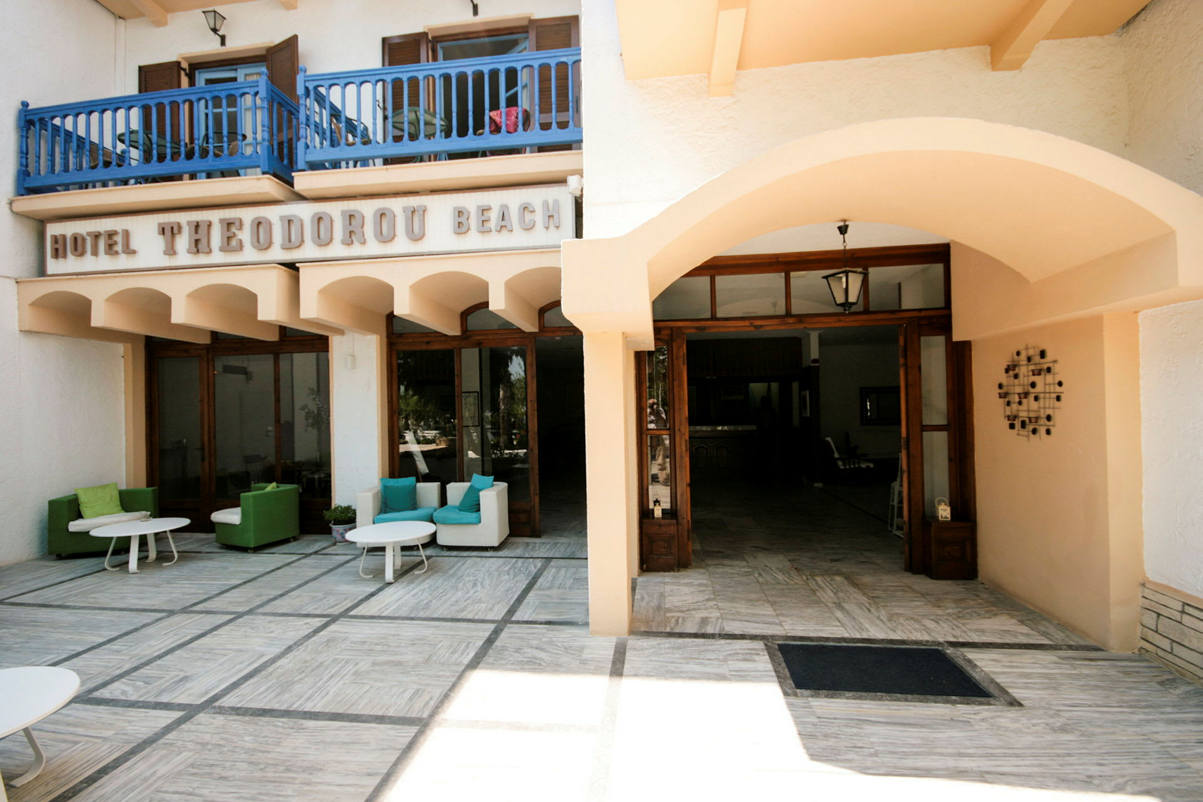 Entré till Hotel Theodoru Beach med sittplatser utomhus. (AI-genererad text)