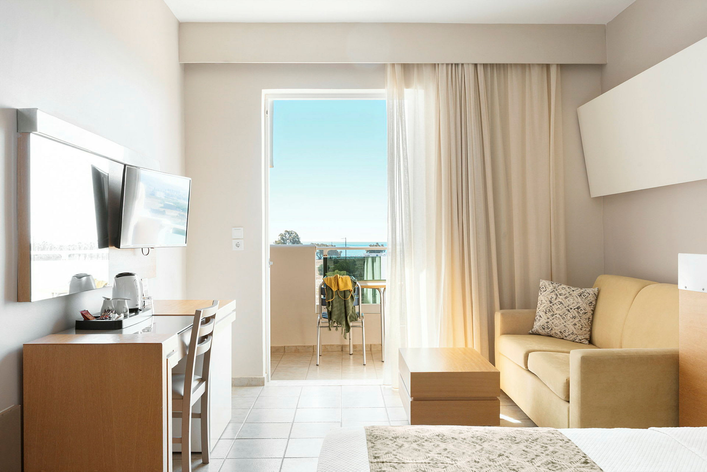 Hotellrum med balkong, TV, skrivbord, soffa och säng. (AI-genererad text)