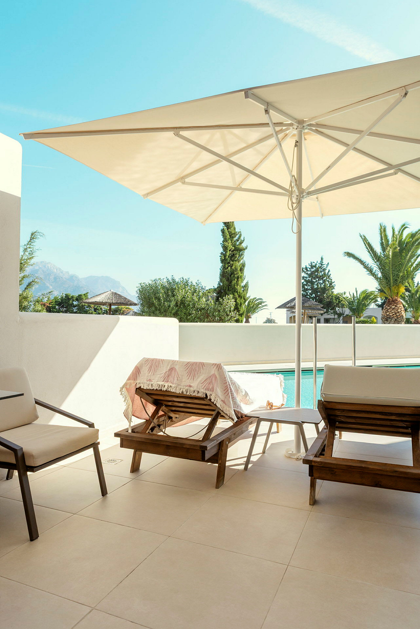 Bild på en terrass med solstolar, parasoll och pool i bakgrunden. (AI-genererad text)