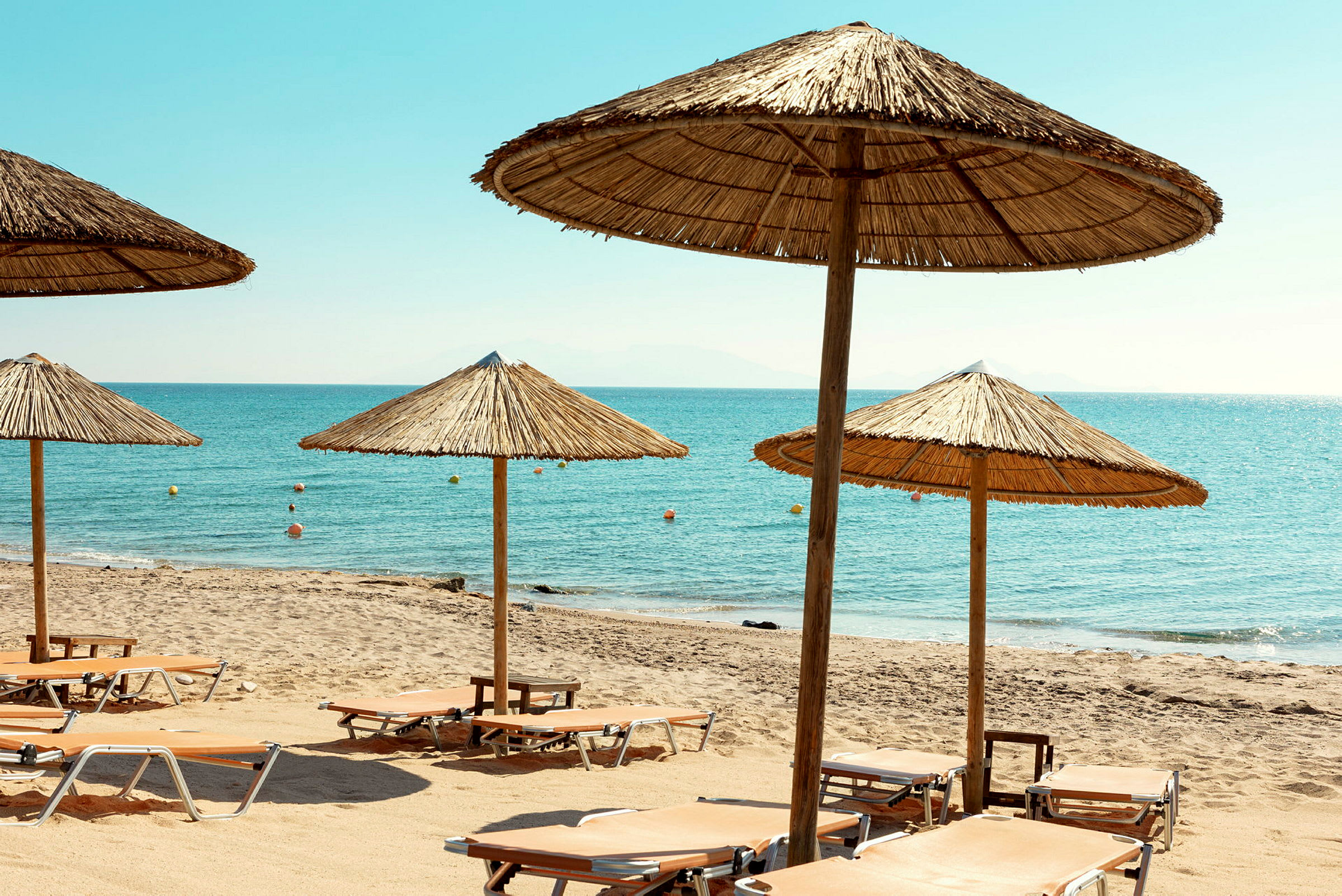 Strand med solstolar och parasoller vid havet. (AI-genererad text)