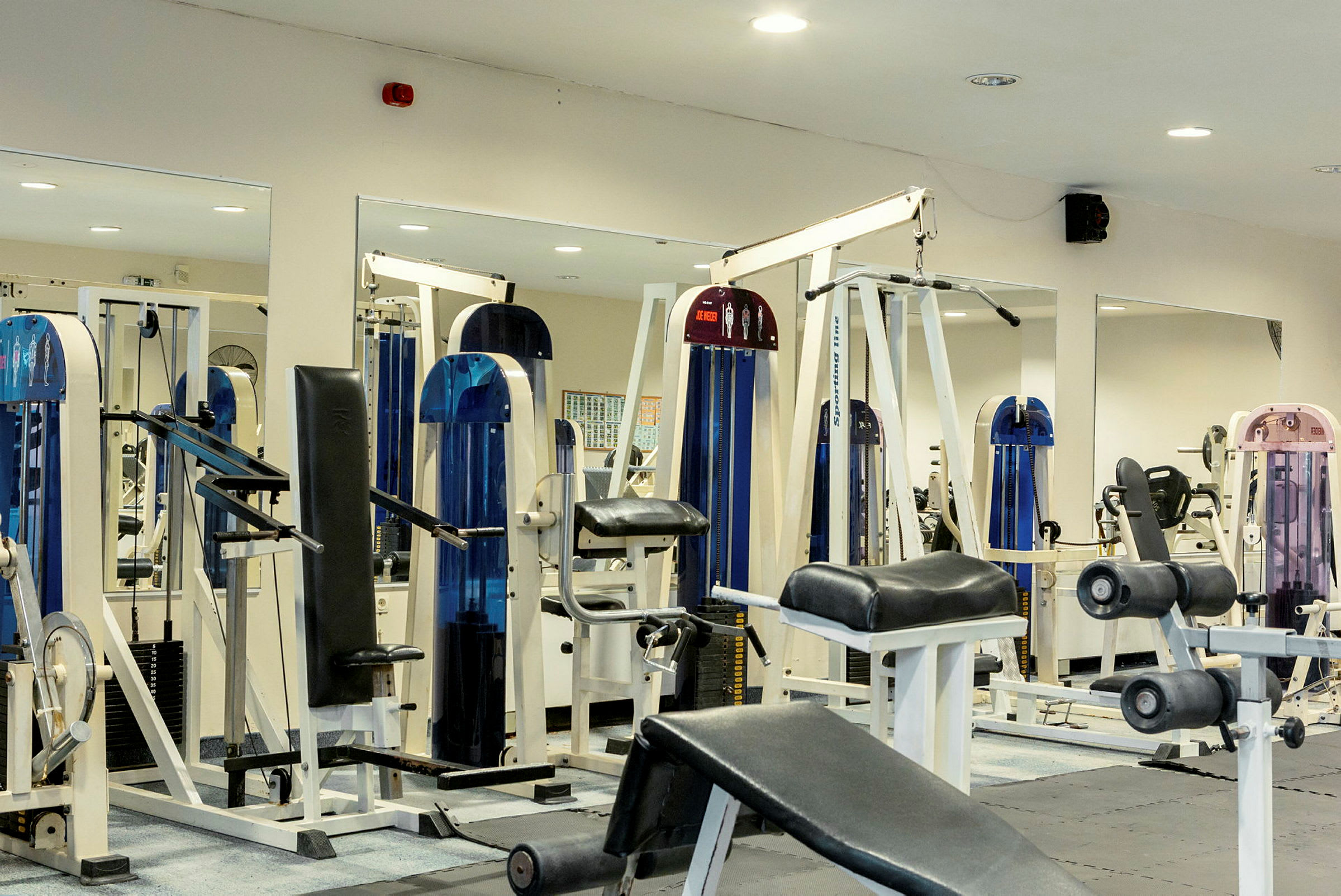 Bild på ett gym med olika träningsmaskiner och utrustning. (AI-genererad text)