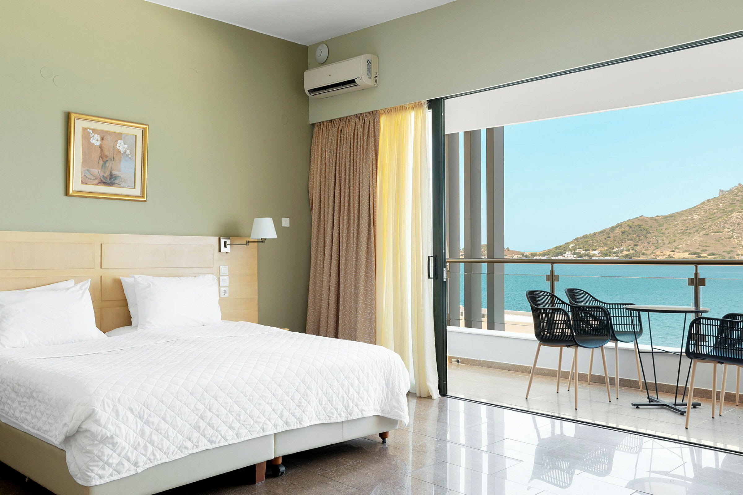 Hotellrum med en dubbelsäng och en balkong med utsikt över havet. (AI-genererad text)
