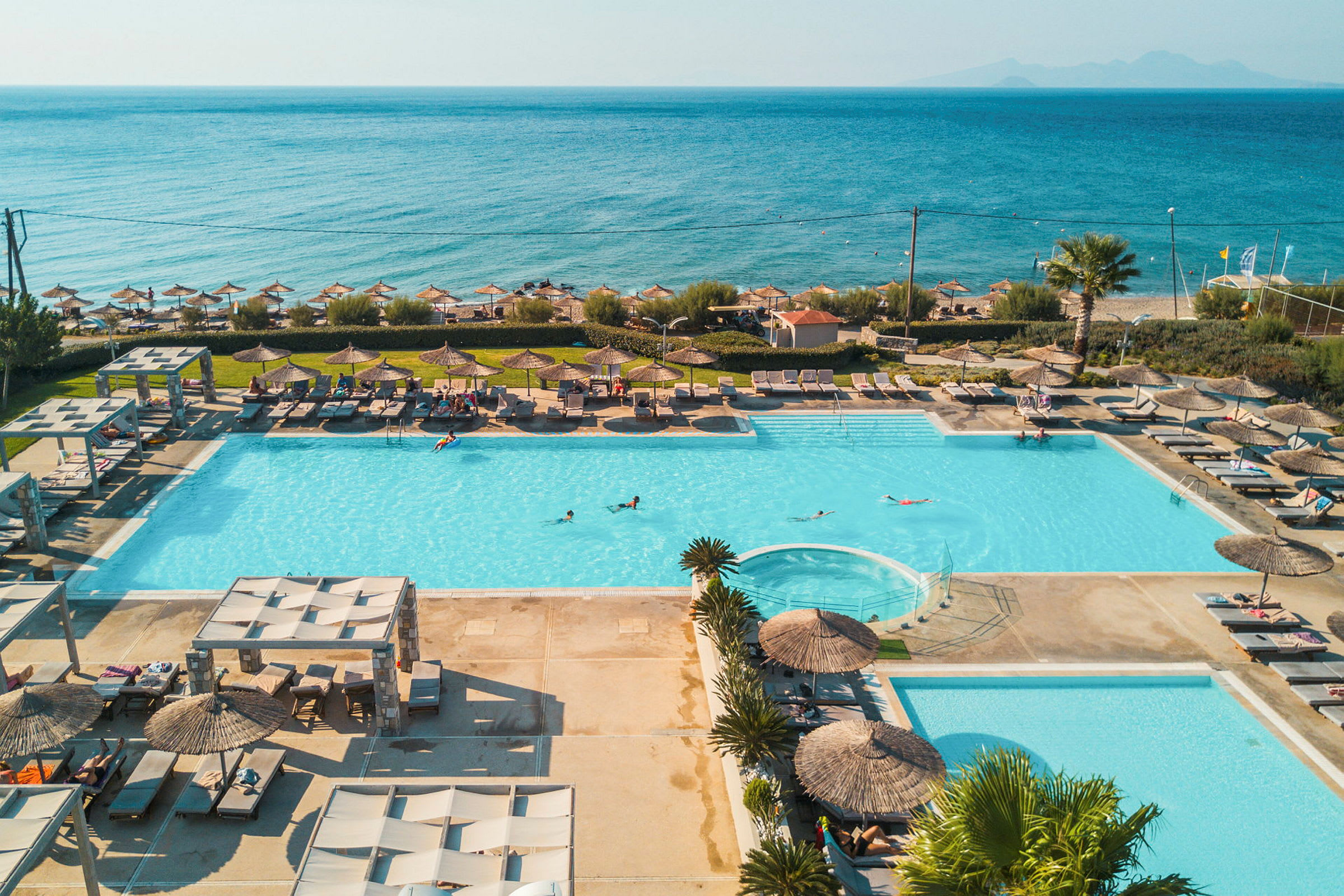 Stor pool vid stranden, med solstolar och parasoller runt. (AI-genererad text)