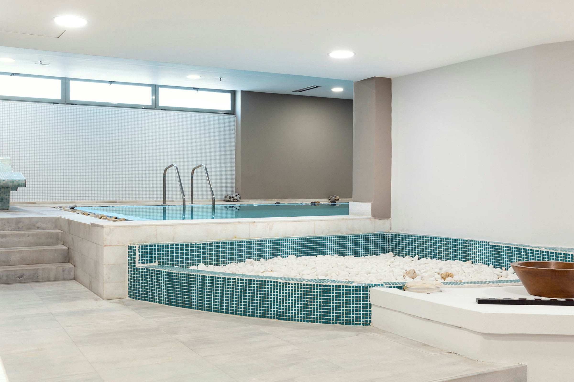 Ett inomhusspa med en pool och dekorativa vita stenar. (AI-genererad text)