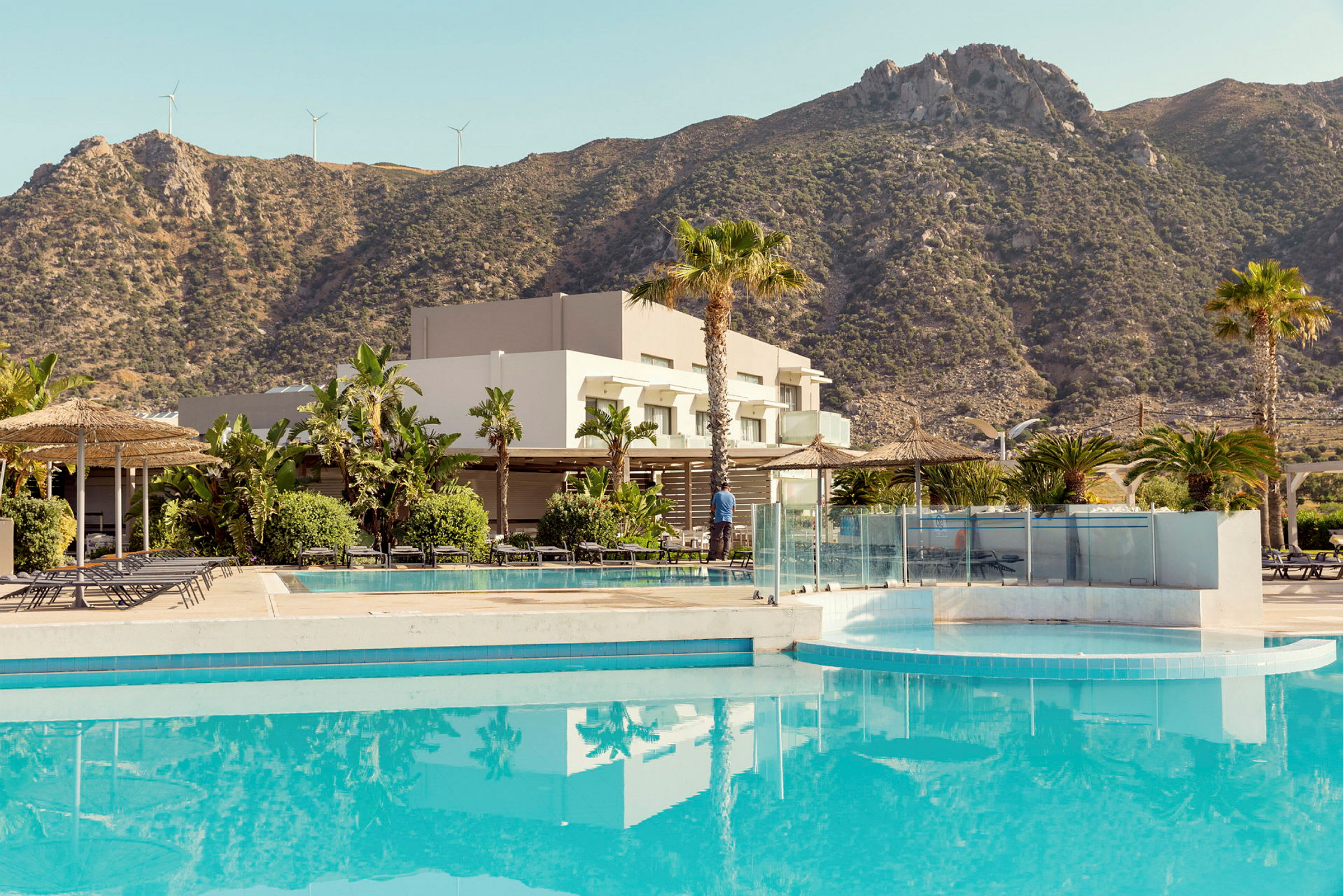 En utomhuspool framför ett hotell med berg i bakgrunden. (AI-genererad text)