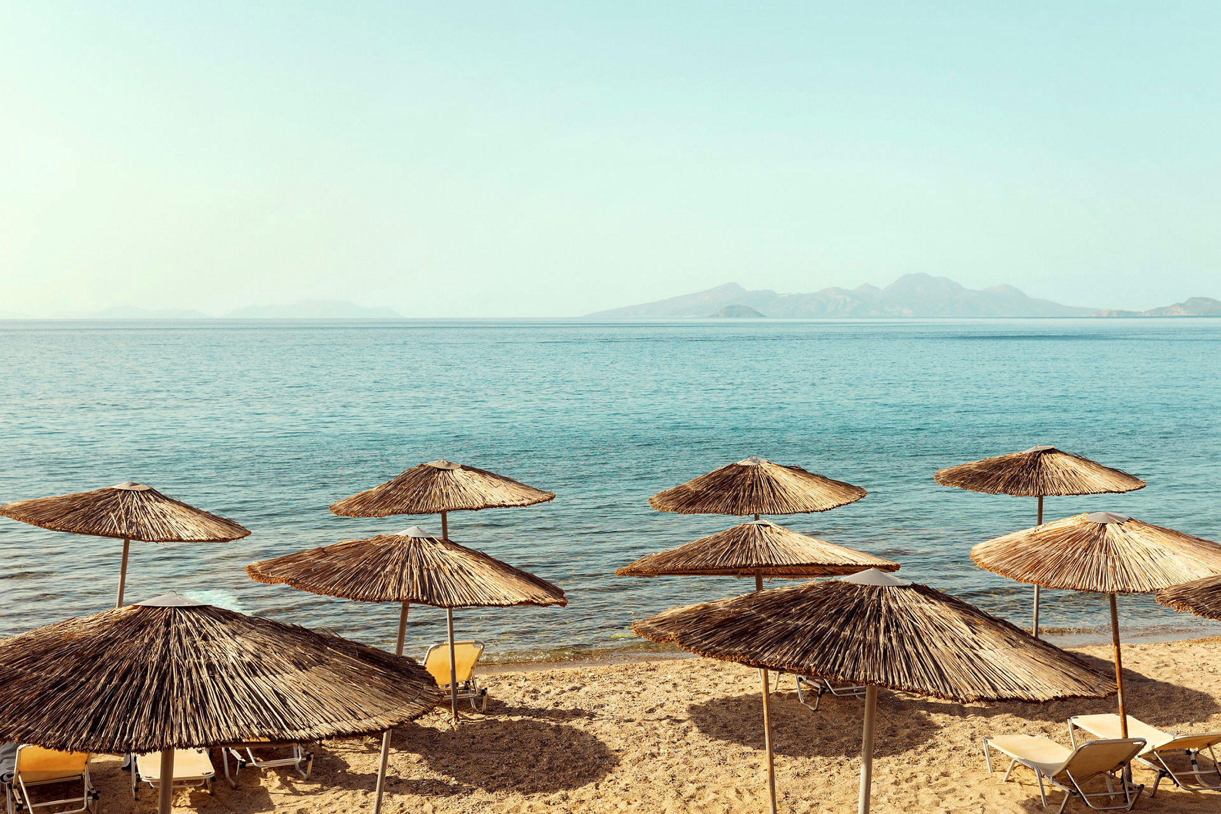 Strand med parasoller av halm vid havet. (AI-genererad text)