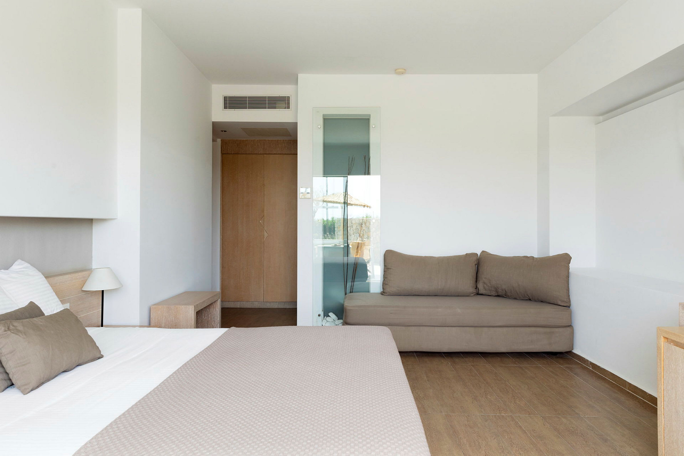 Ett hotellrum med en säng, en soffa och ljusa väggar. (AI-genererad text)