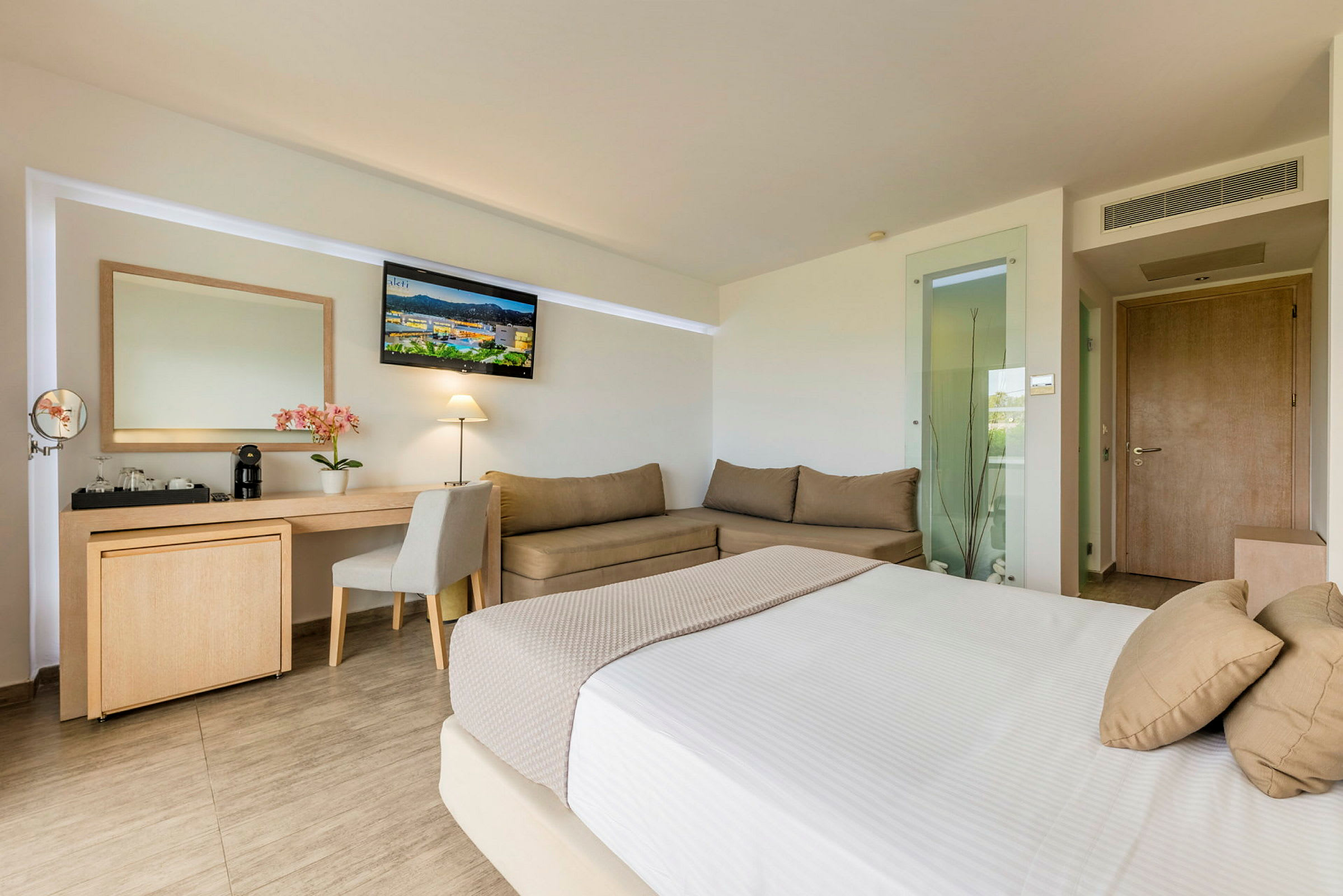 Hotelrum med säng, skrivbord, soffa och TV. (AI-genererad text)