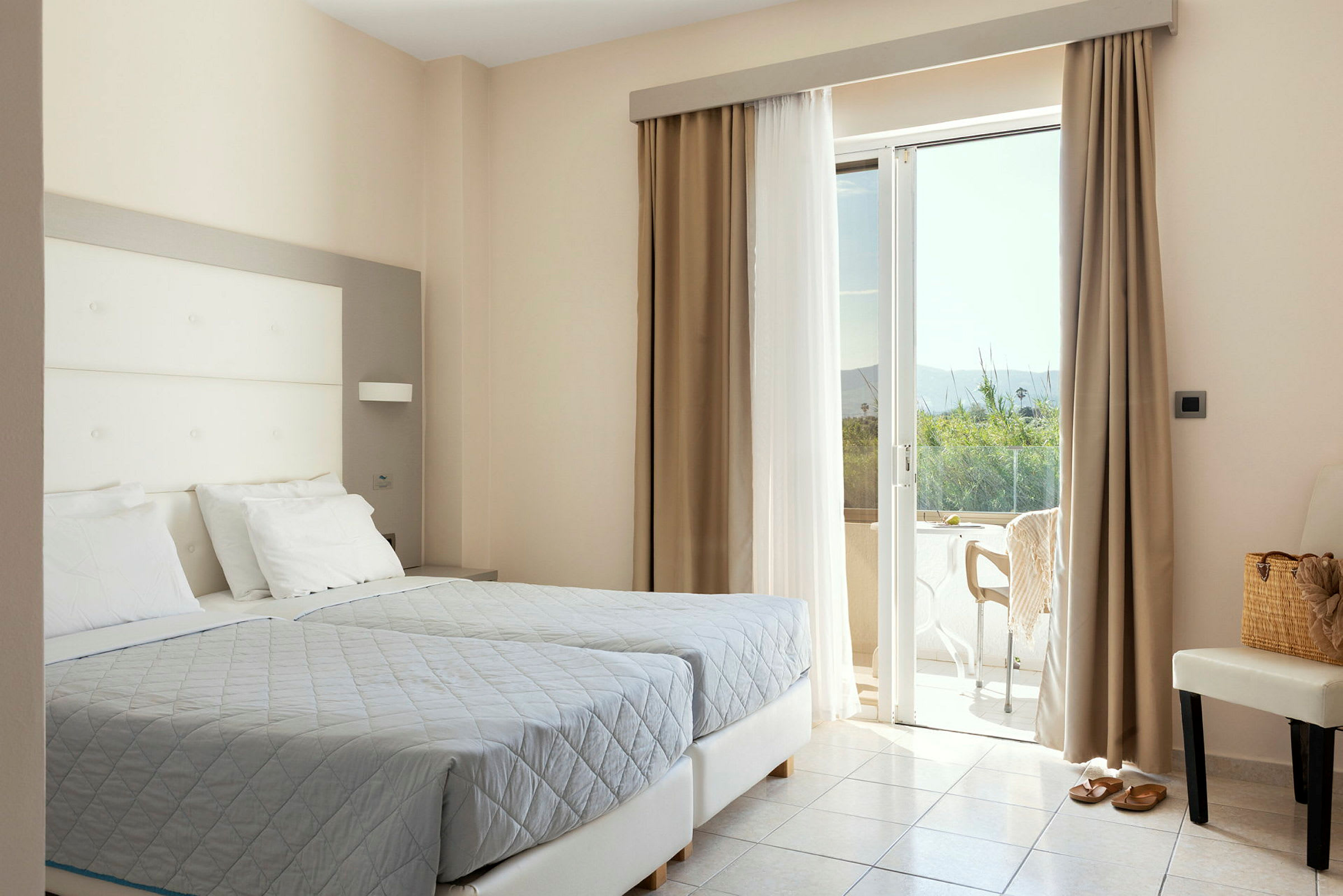 Ett hotellrum med två sängar, en stol och en öppning mot en terrass. (AI-genererad text)