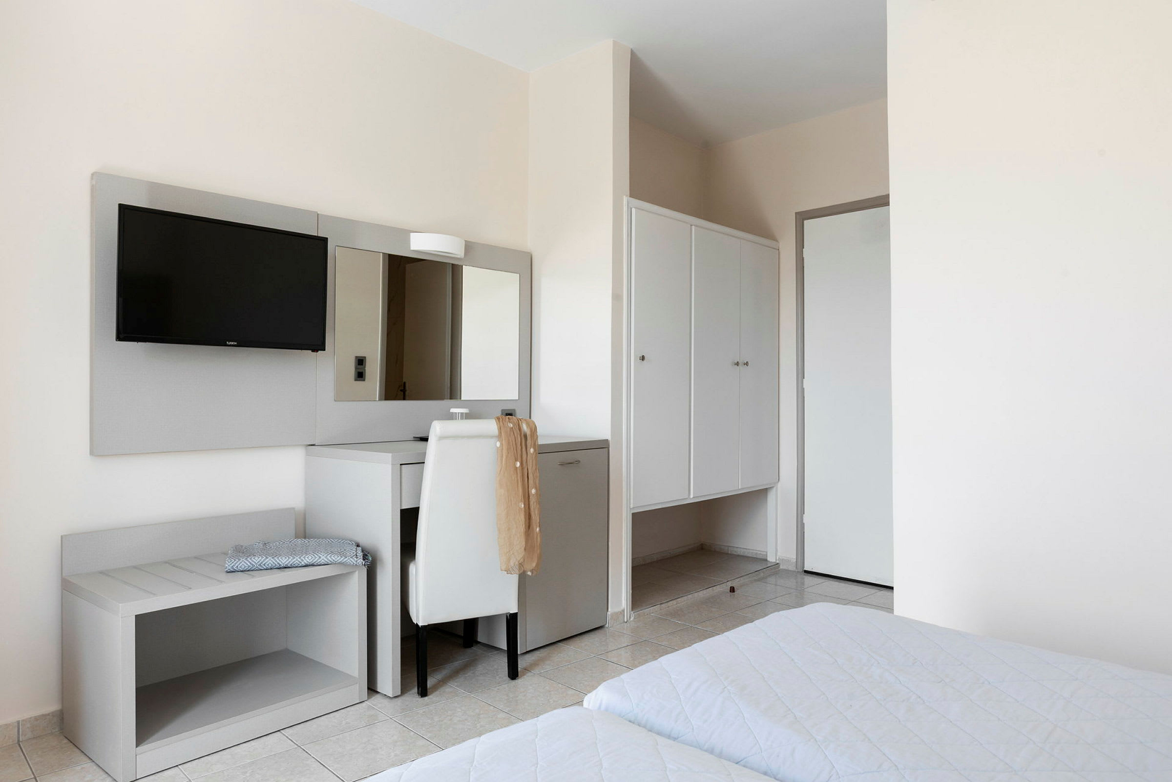 Hotellrum med sängar, skrivbord, spegel och garderob. (AI-genererad text)