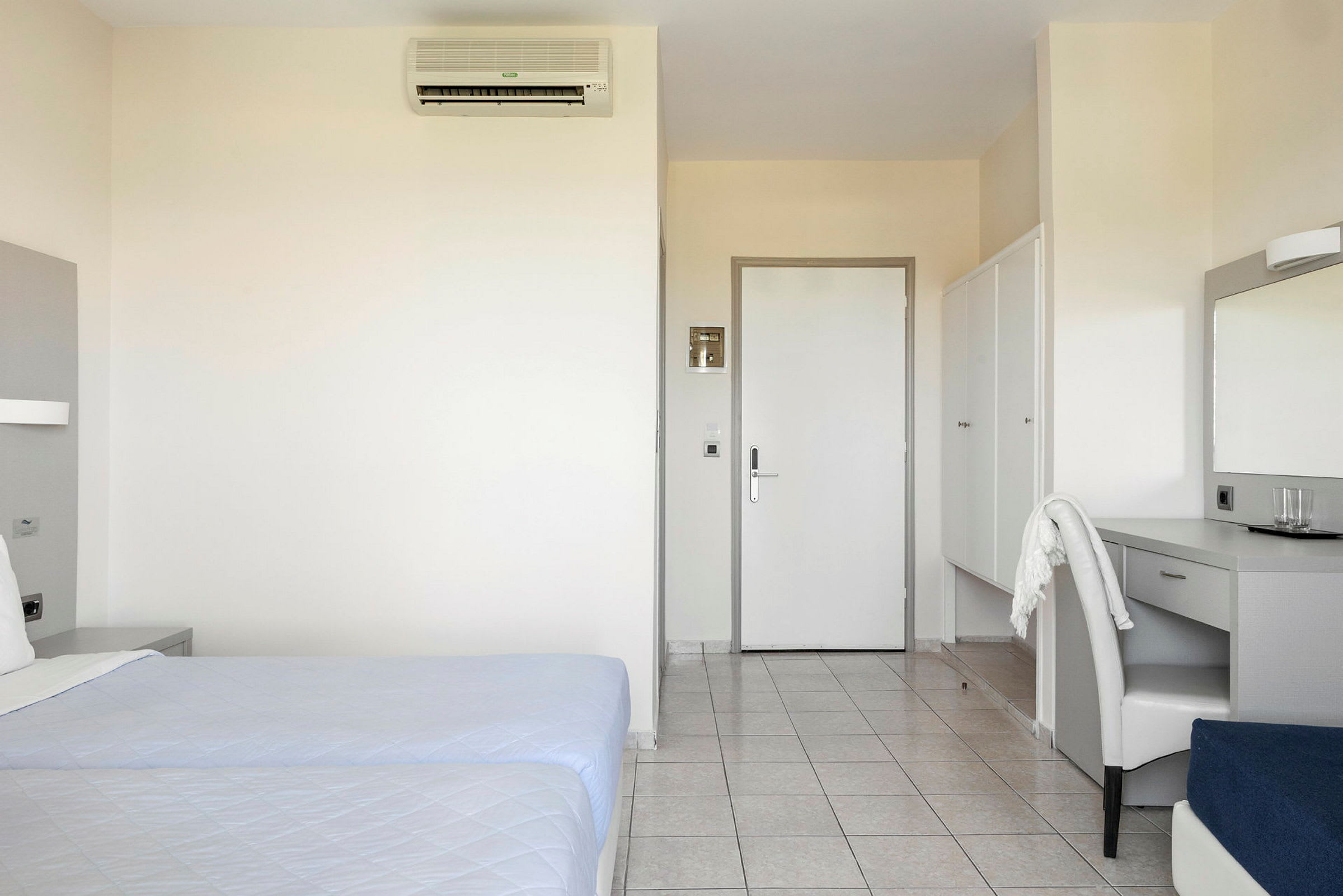 En hotellrum med dubbelsängar, skrivbord och garderober. (AI-genererad text)