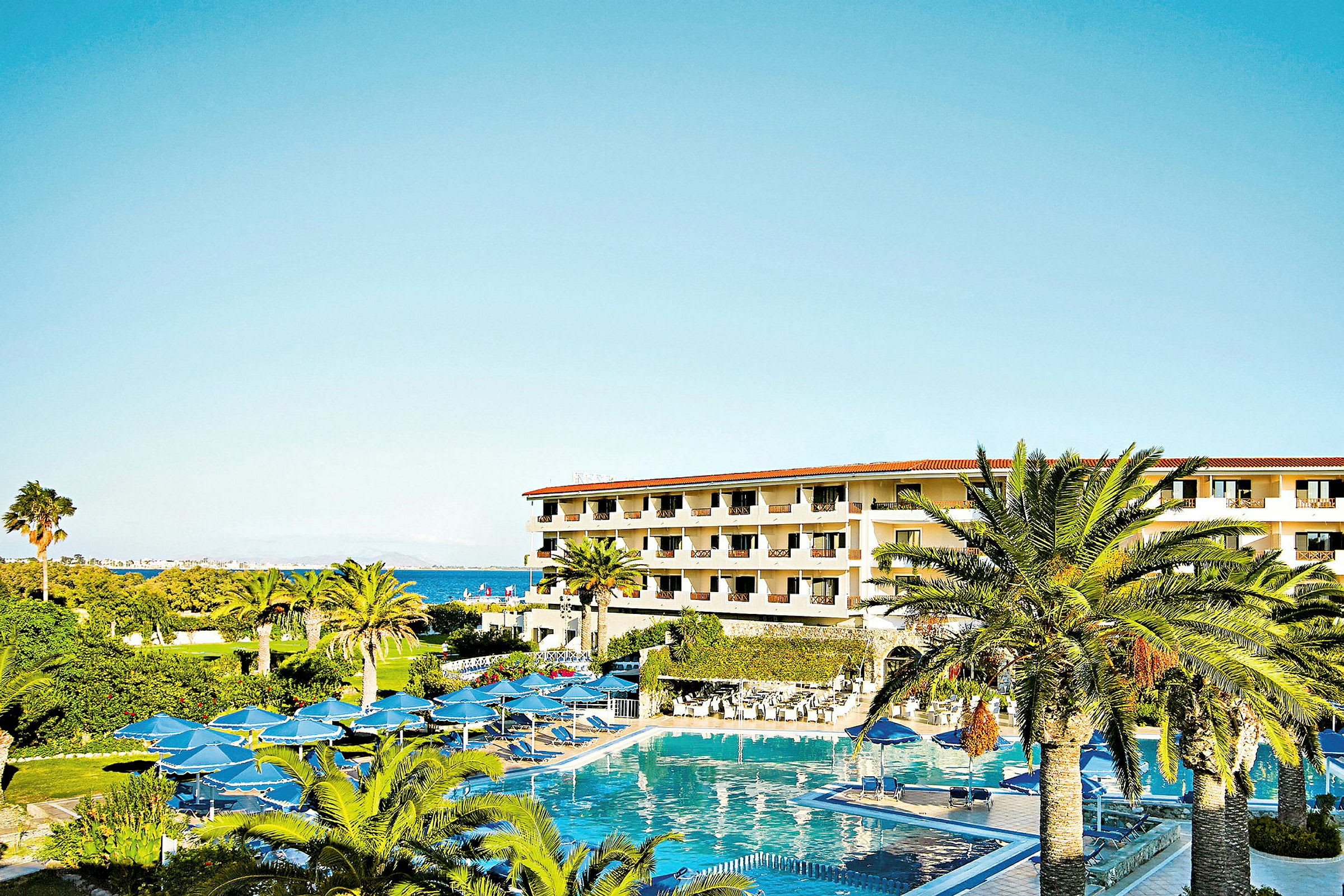 Hotellbyggnad med flera våningar omgiven av palmer och en stor pool. (AI-genererad text)