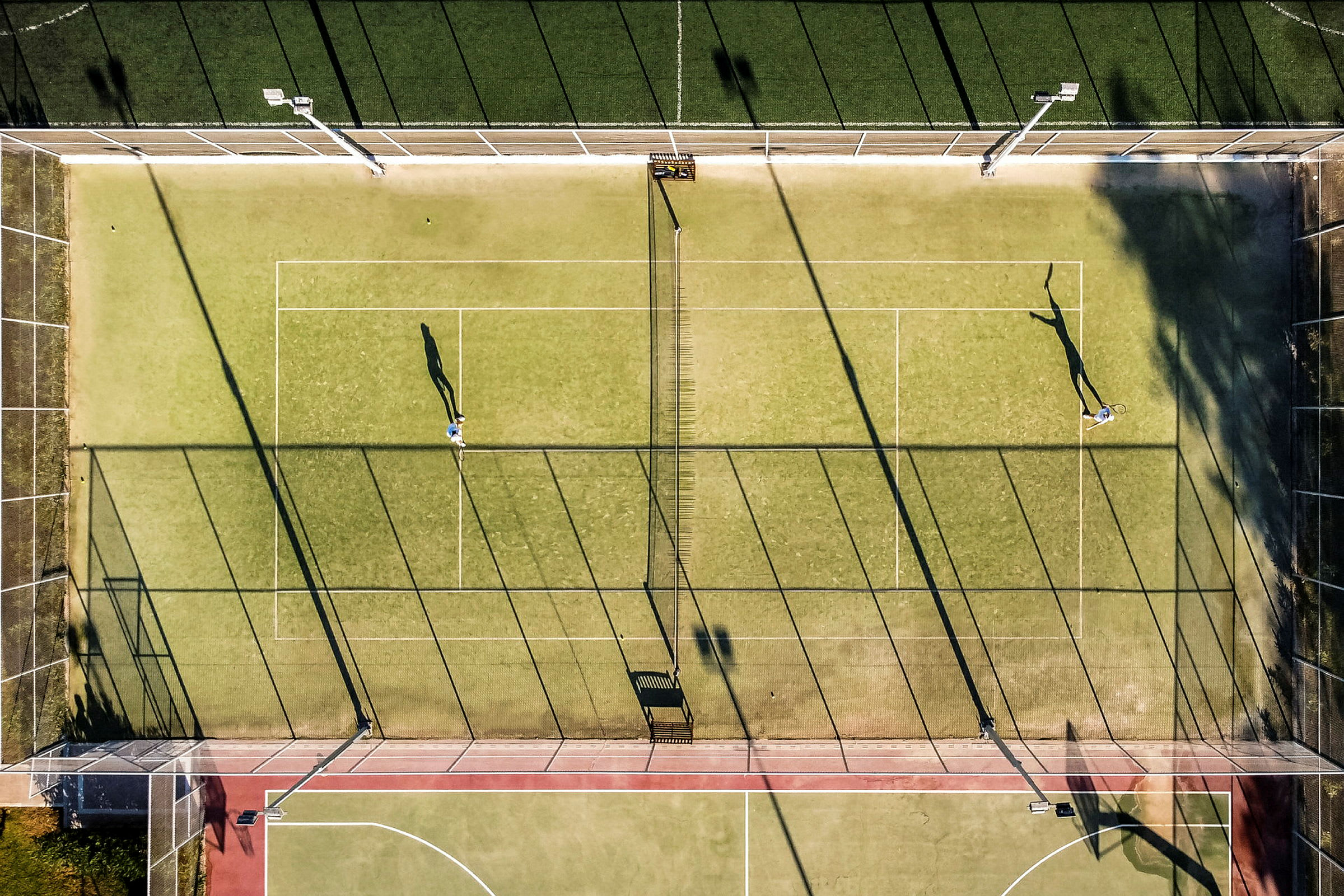Flygbild på tennisplan med två spelare. (AI-genererad text)