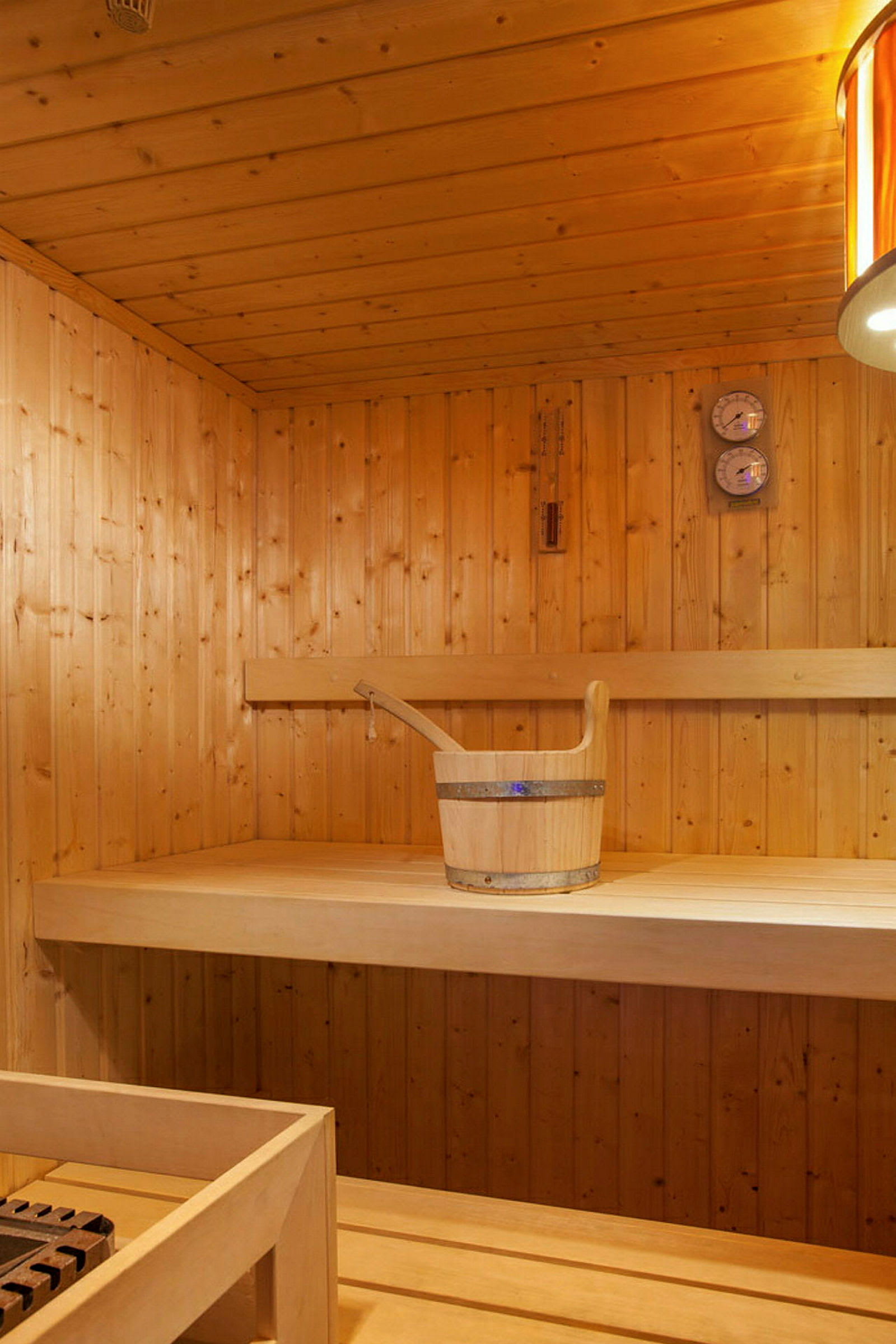 Interiör av en bastu med träpaneler och en hink på en bänk. (AI-genererad text)