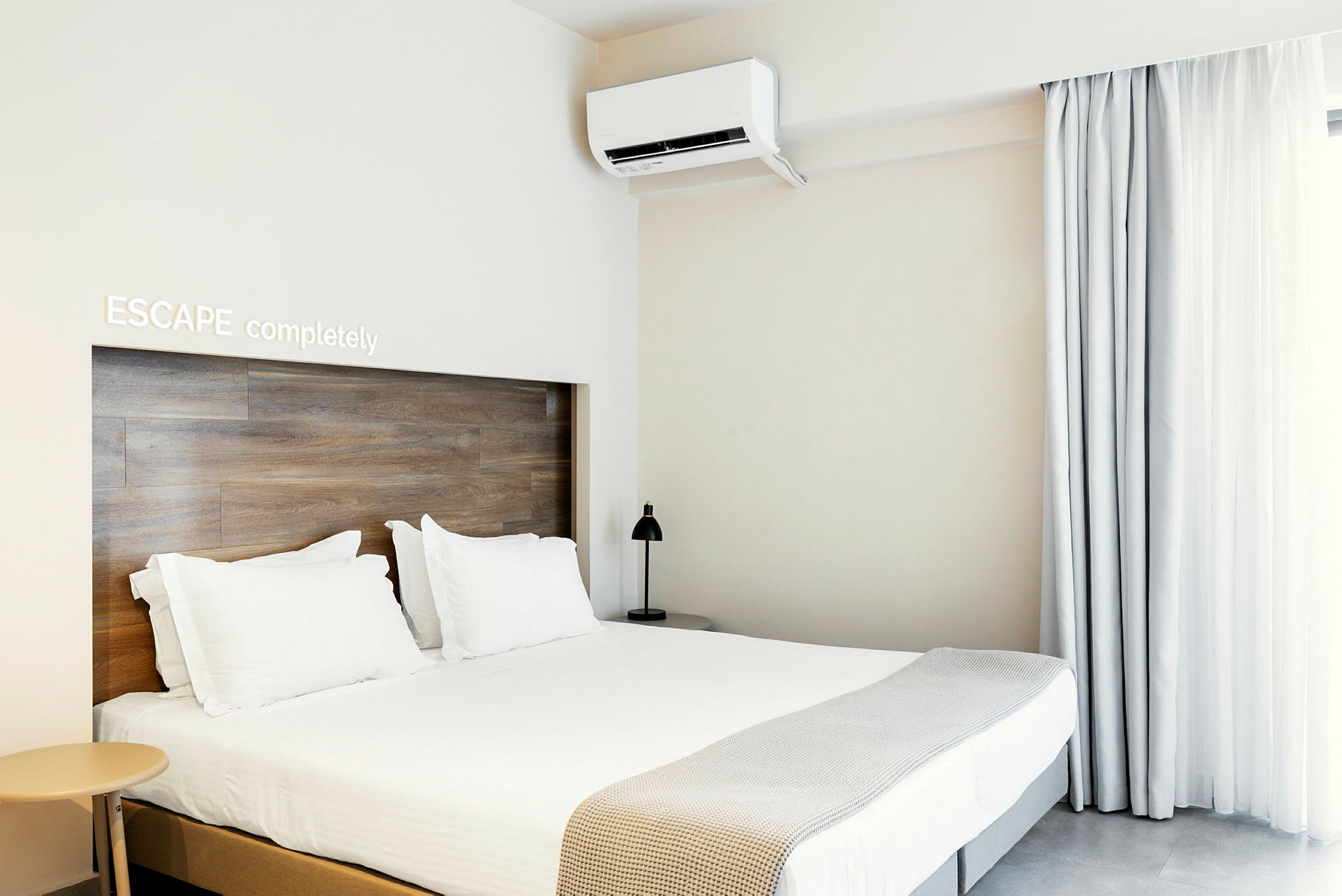 Ett modernt hotellrum med dubbelsäng, ljus inredning och luftkonditionering. (AI-genererad text)