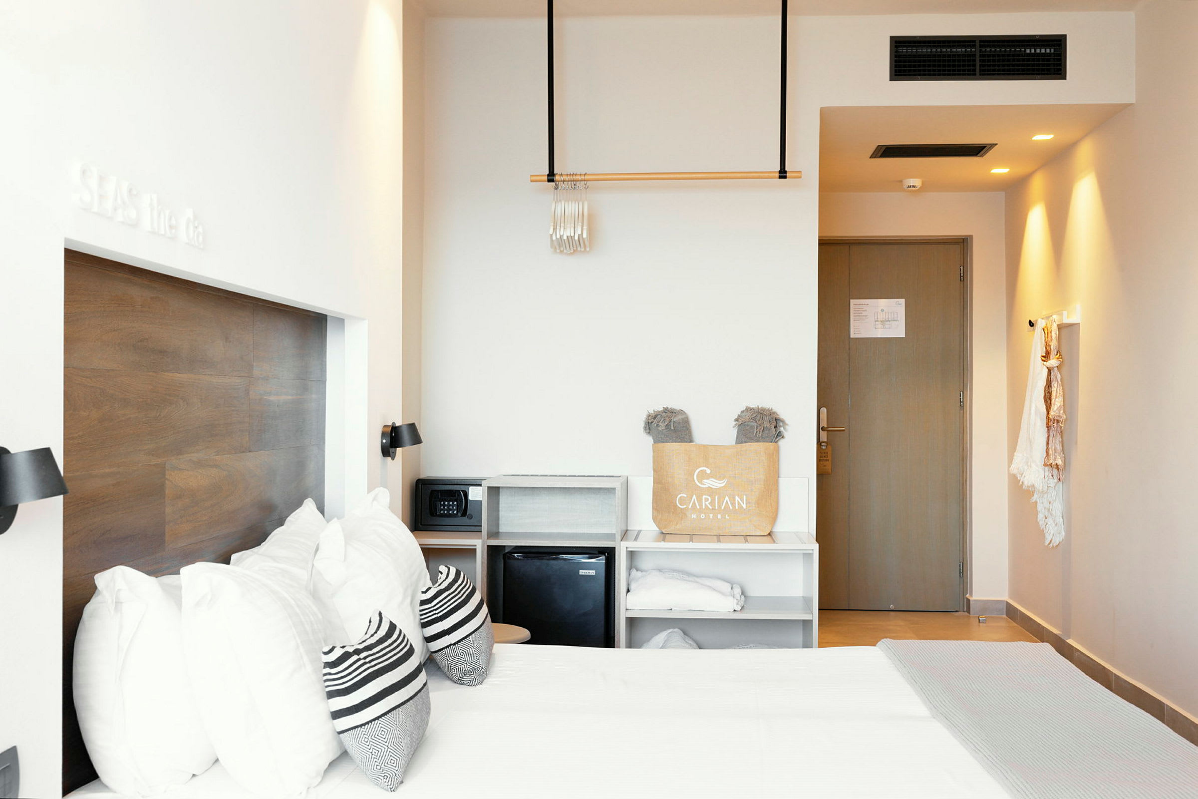Ett hotellrum med en dubbelsäng, träpanel på väggen, förvaringshyllor och en dörr. (AI-genererad text)