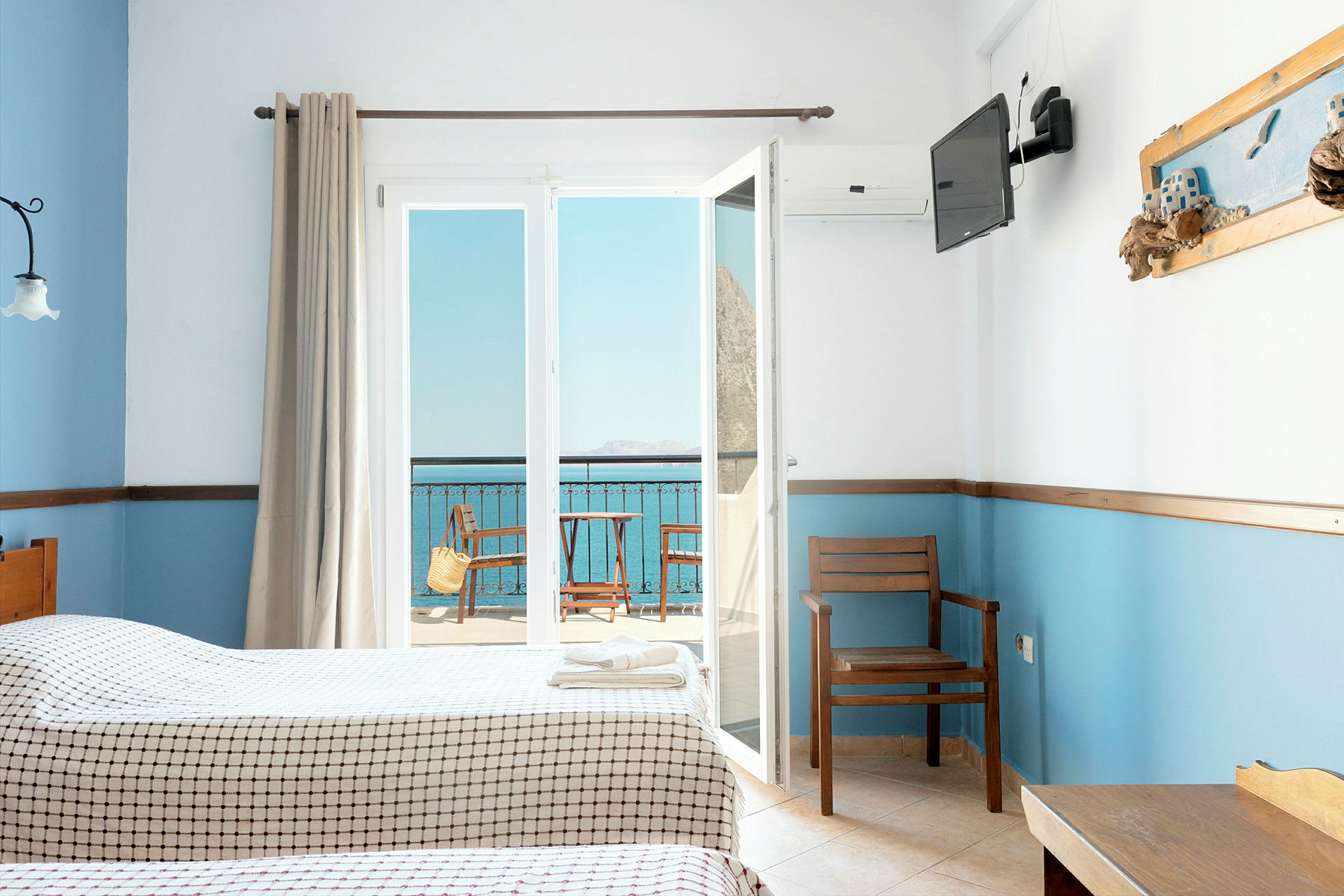 Hotellrum med två sängar, utsikt mot en balkong och havet. (AI-genererad text)