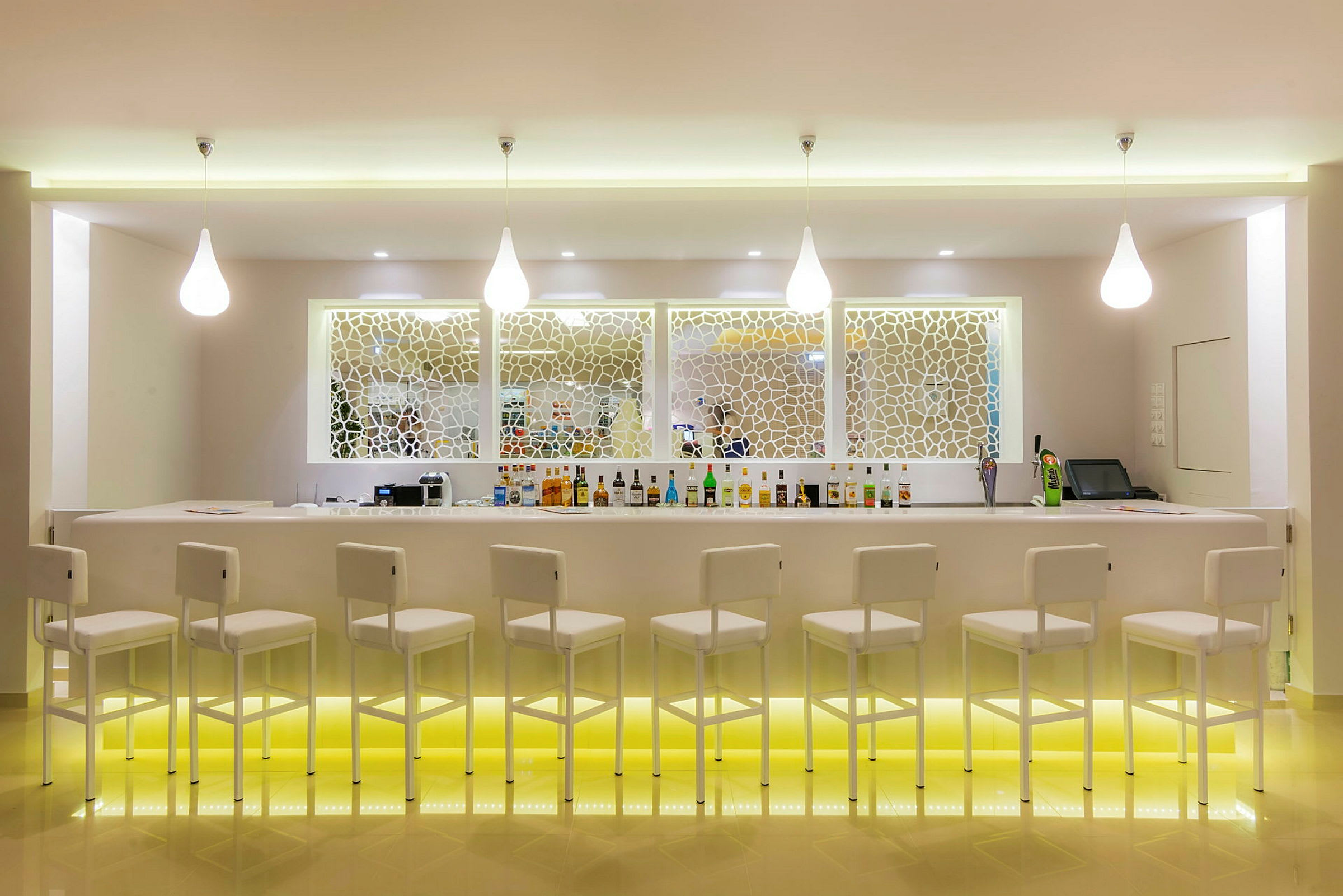 En modern bar med vita barstolar och en upplyst bardisk. (AI-genererad text)