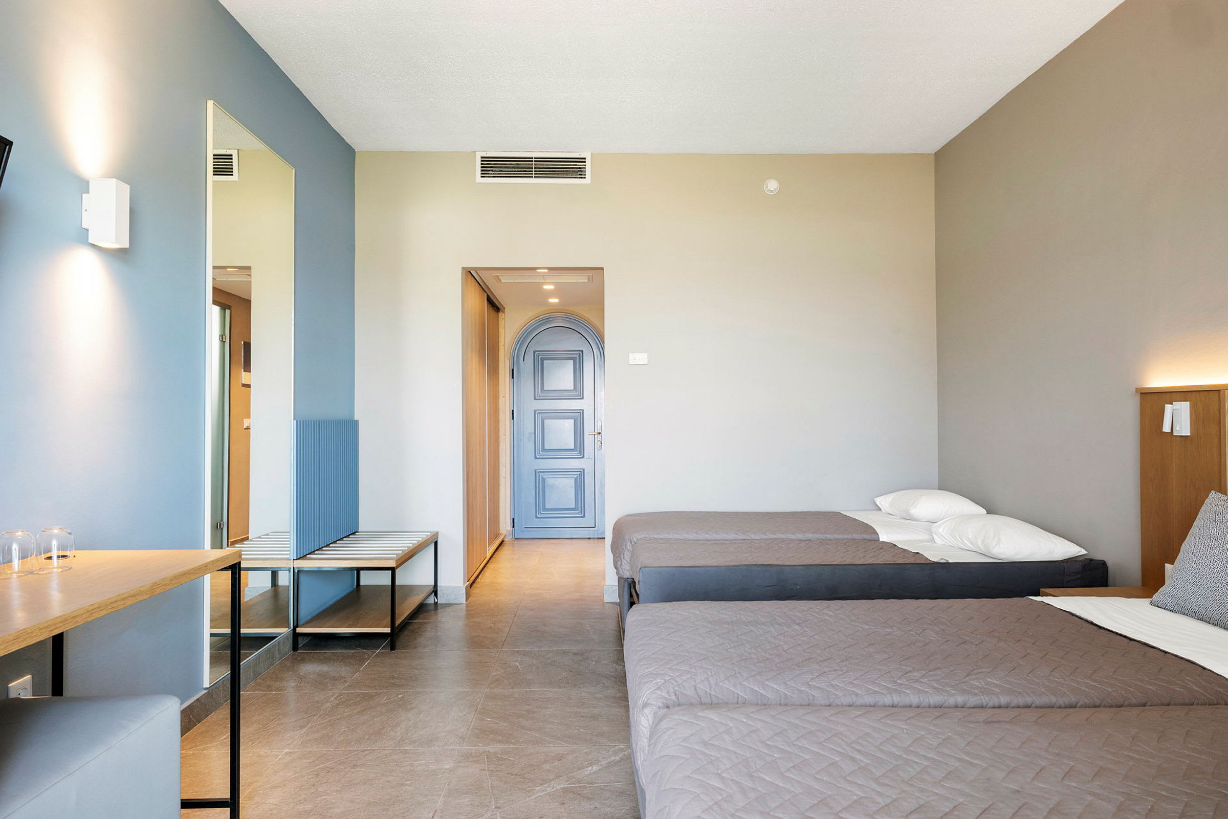Ett hotellrum med två enkelsängar, ett skrivbord och en blå dörr. (AI-genererad text)