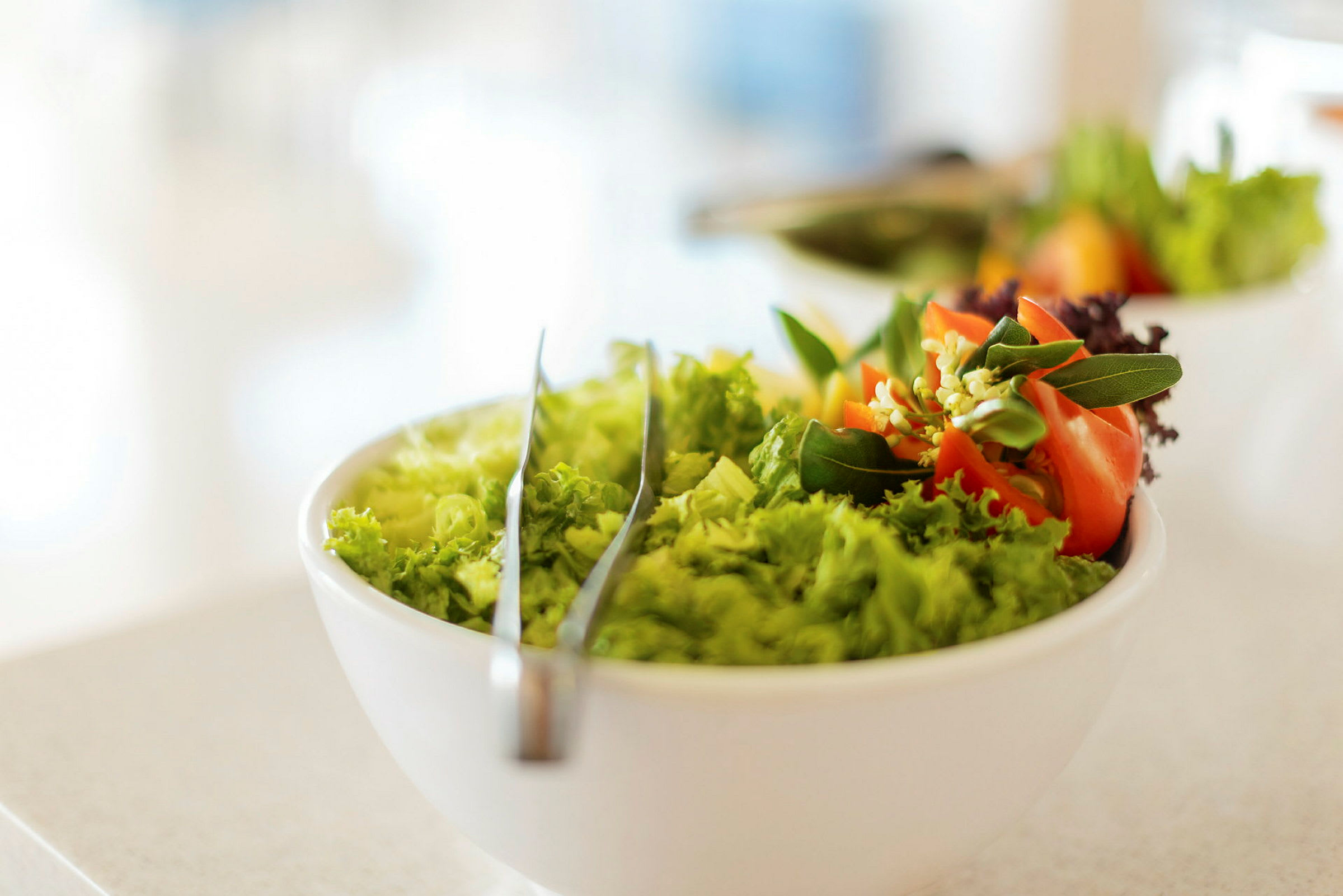 En sallad i en vit skål med dekorativa grönsaker. (AI-genererad text)