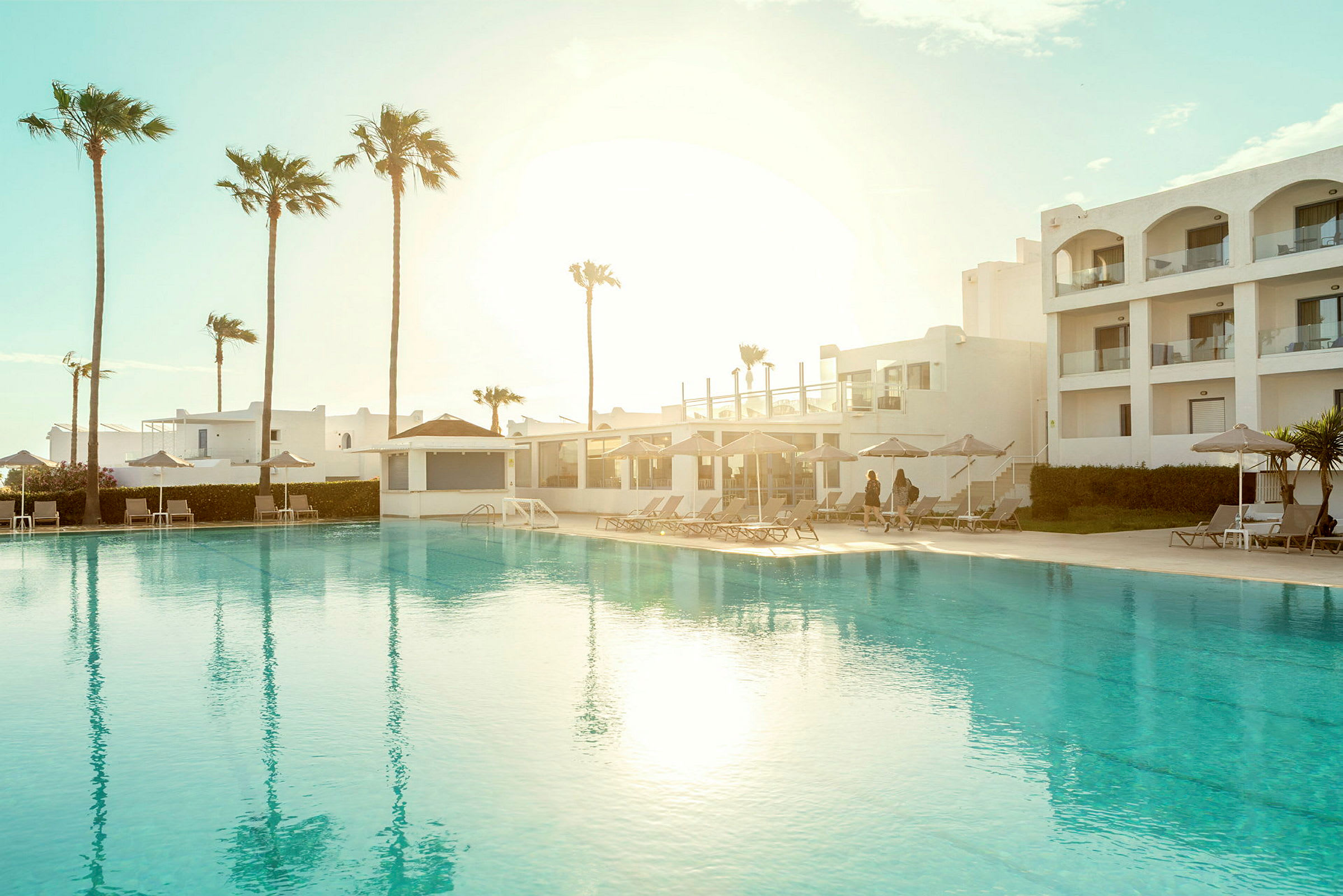 Poolområde vid ett hotell med solstolar och palmer. (AI-genererad text)