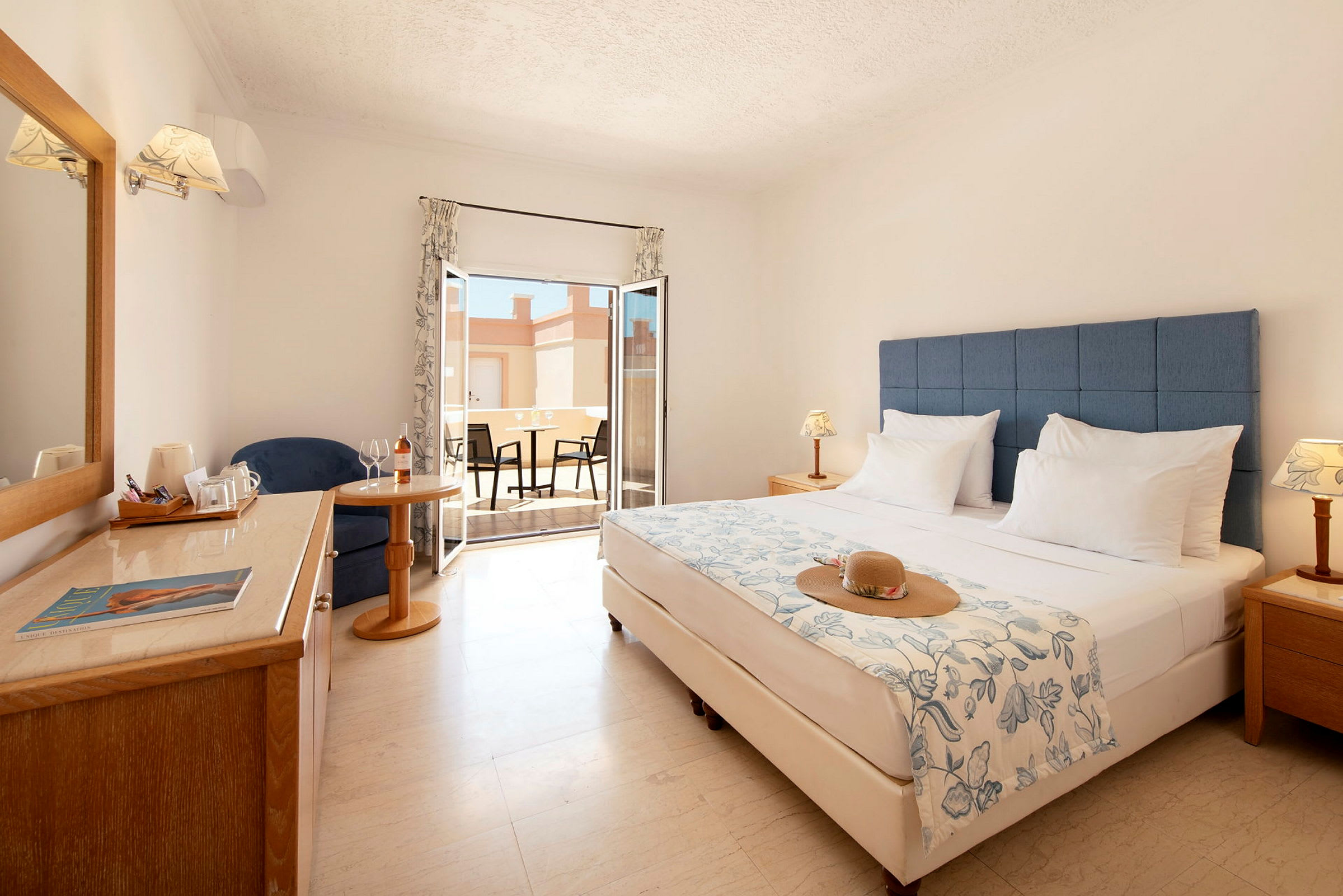 Hotellrum med dubbelsäng, sittplats, fönster och möblerad terrass. (AI-genererad text)