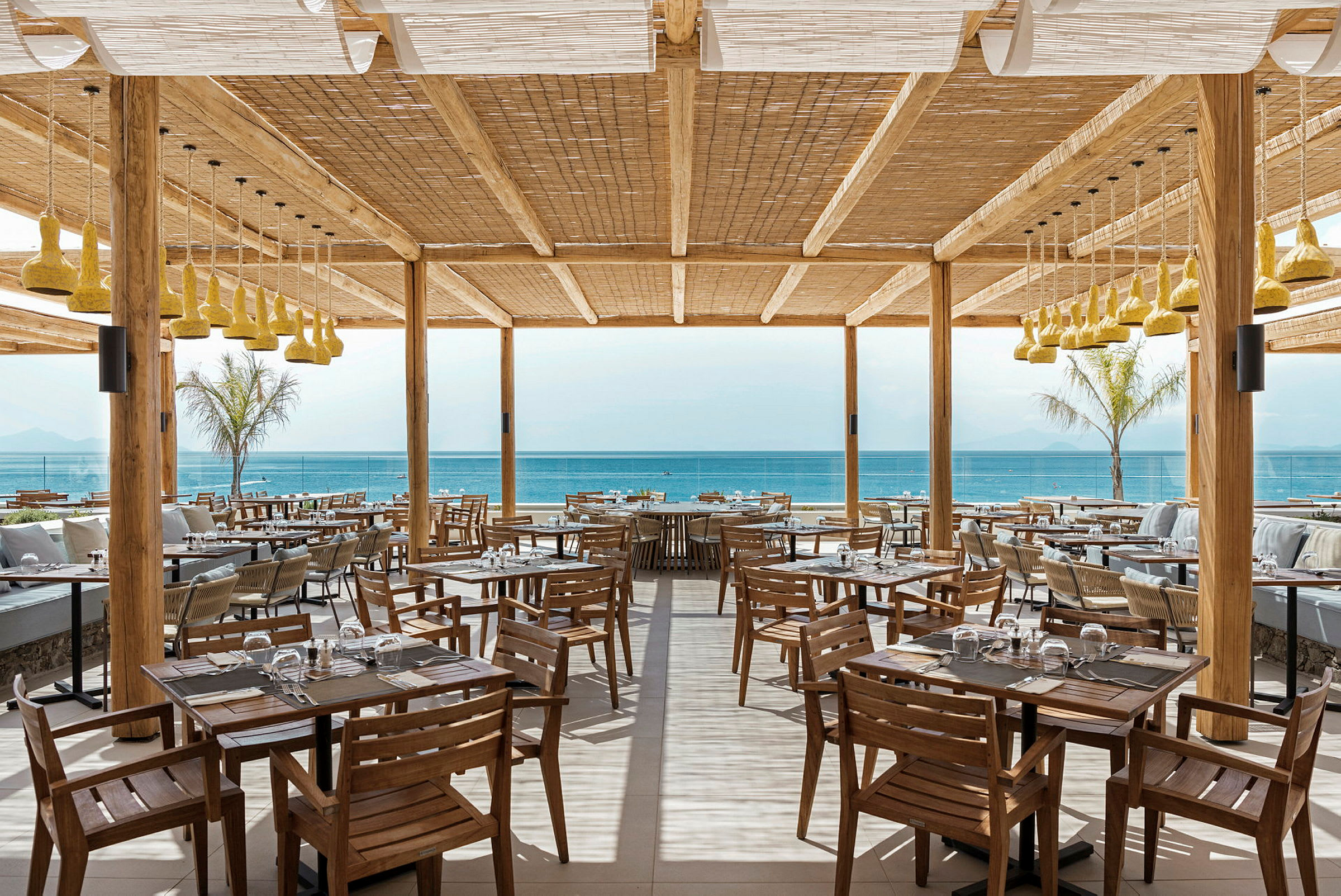 Restaurang med trämöbler och utsikt över havet. (AI-genererad text)