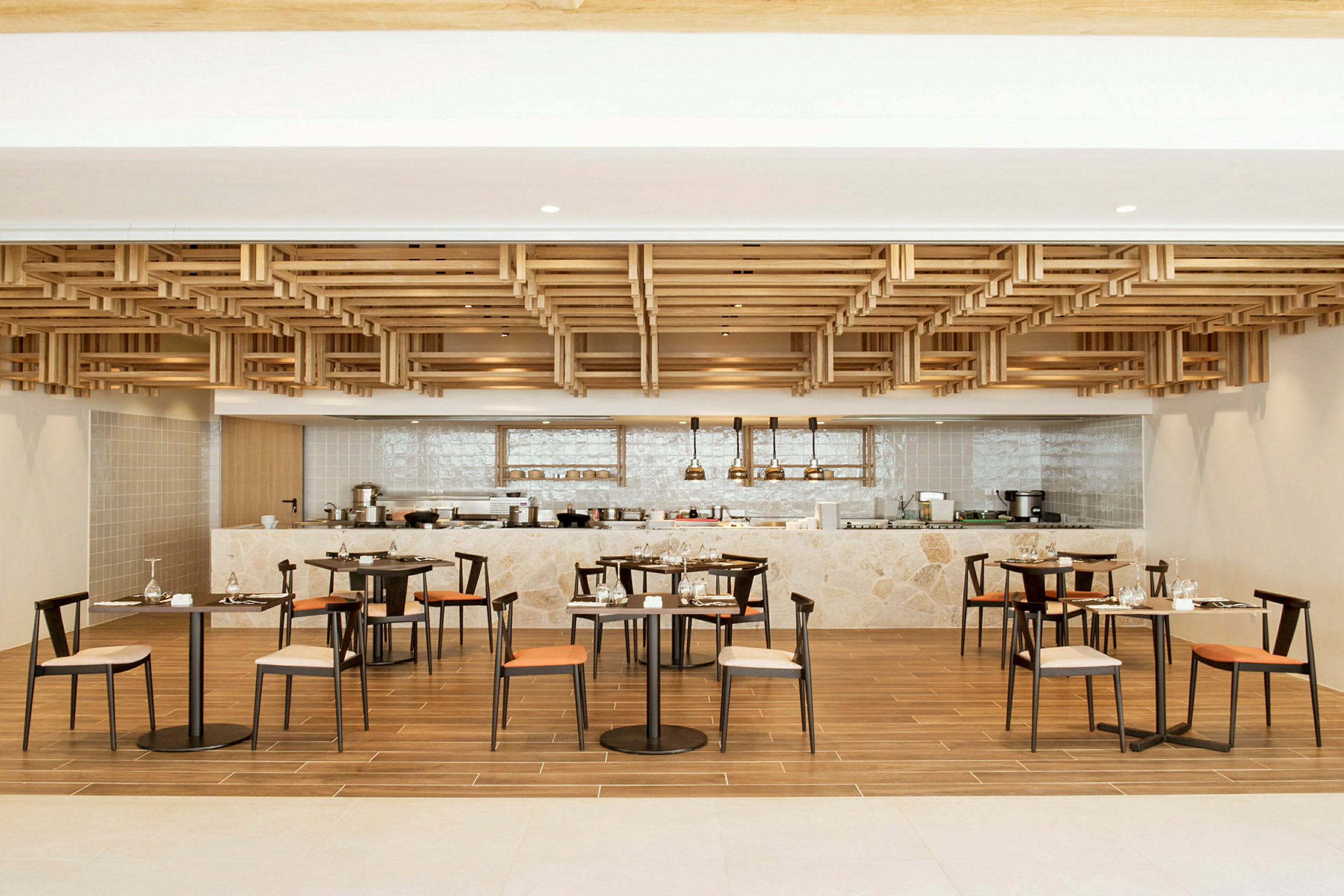 En modern restaurang med trädetaljer i taket, bord och stolar, och en bardisk i bakgrunden. (AI-genererad text)