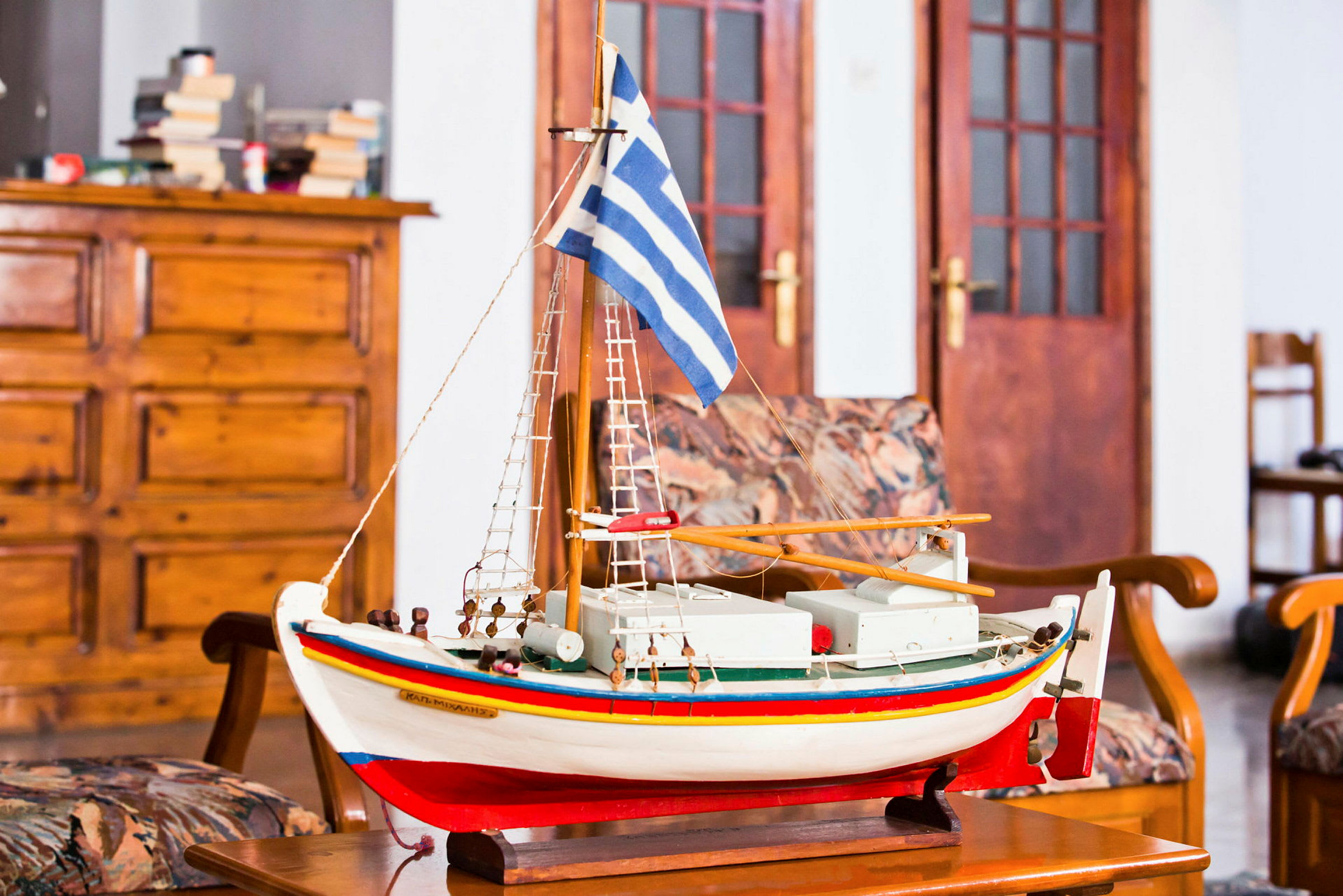 Modell av en båt med grekisk flagga på ett bord. (AI-genererad text)