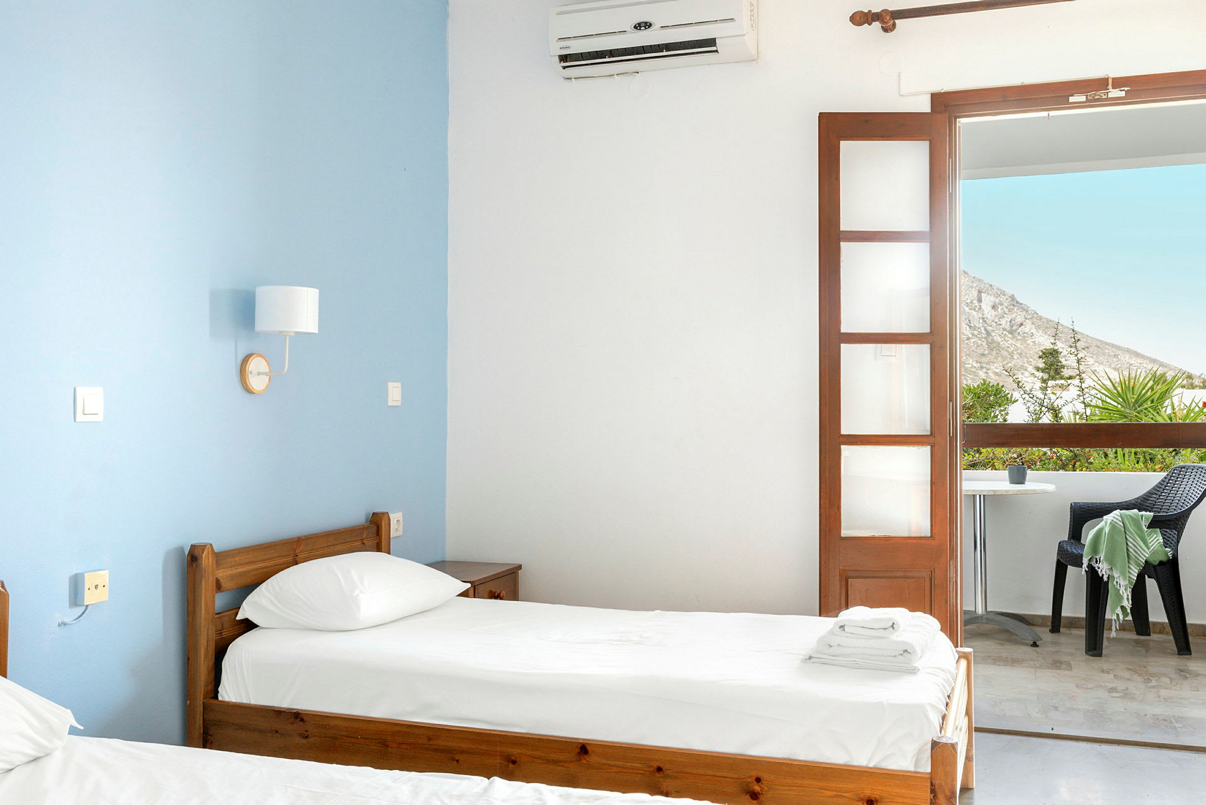 Ett hotellrum med två enkelsängar och en balkong med utsikt. (AI-genererad text)
