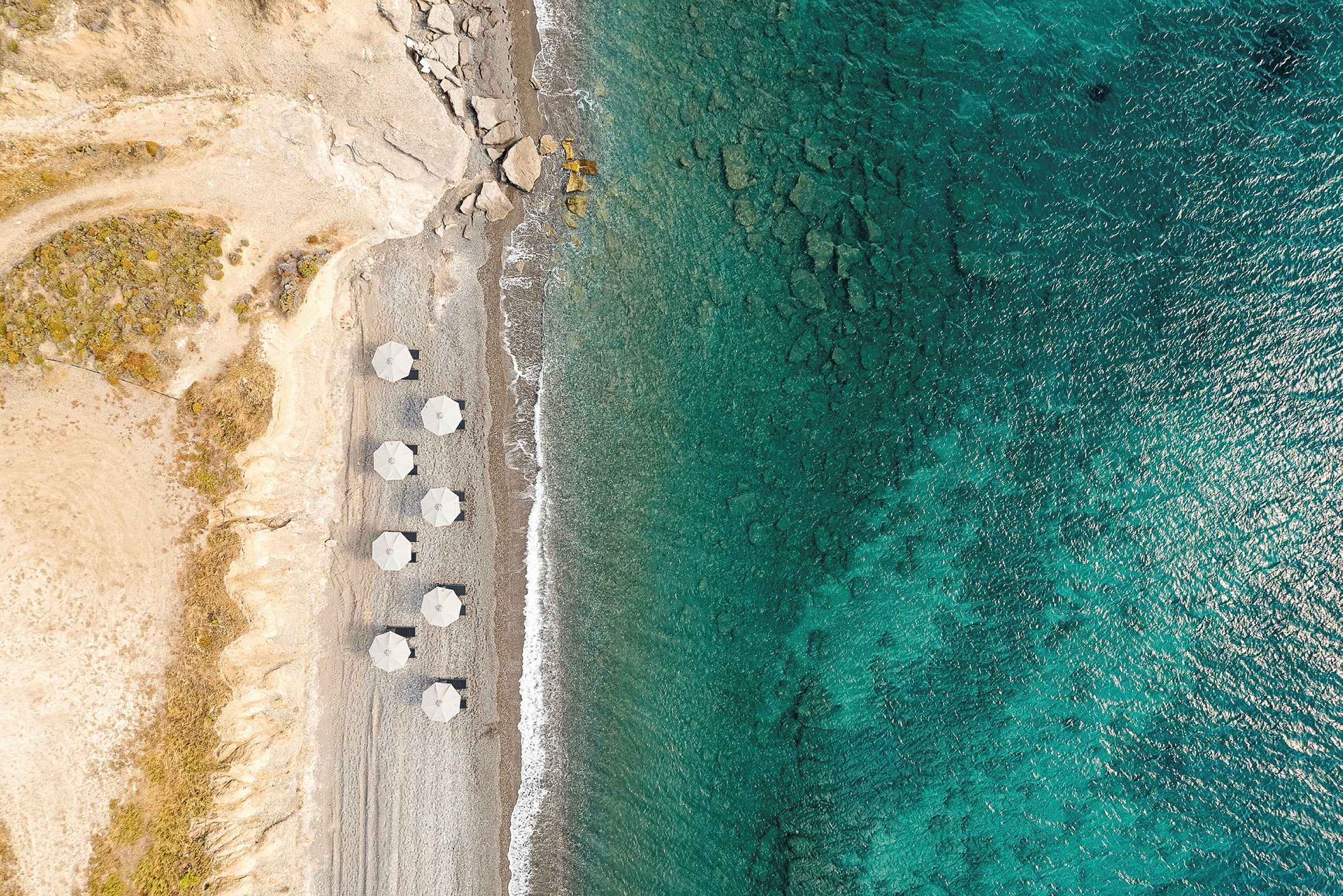 Flygfoto av en strand med parasoller och klart blått hav. (AI-genererad text)